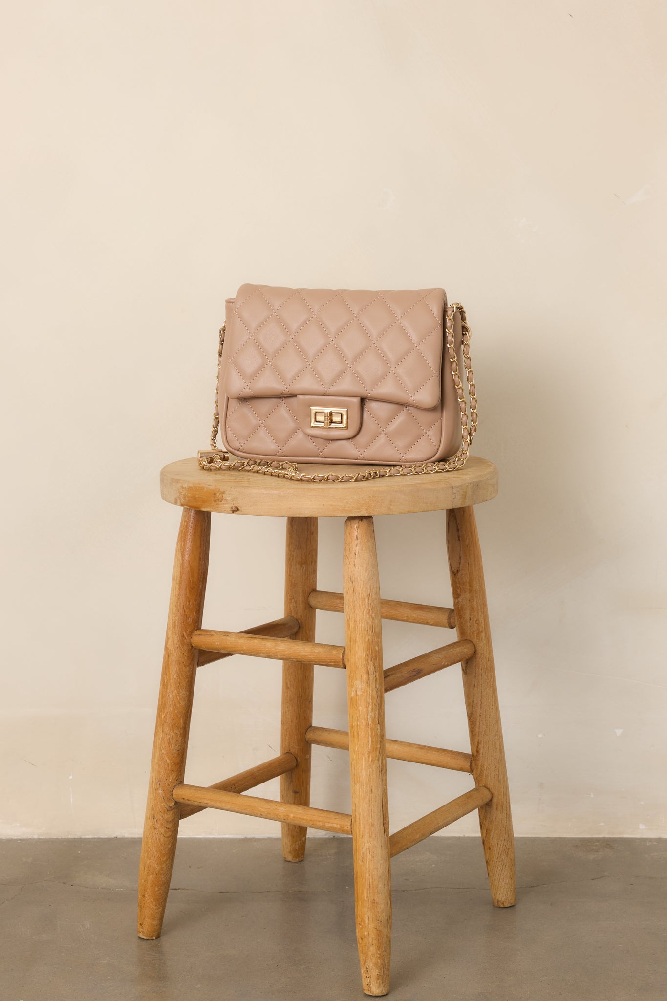 Taupe handbag featuring a quilted exterior, structured flap, front turn-lock closure, and versatile chain strap.
