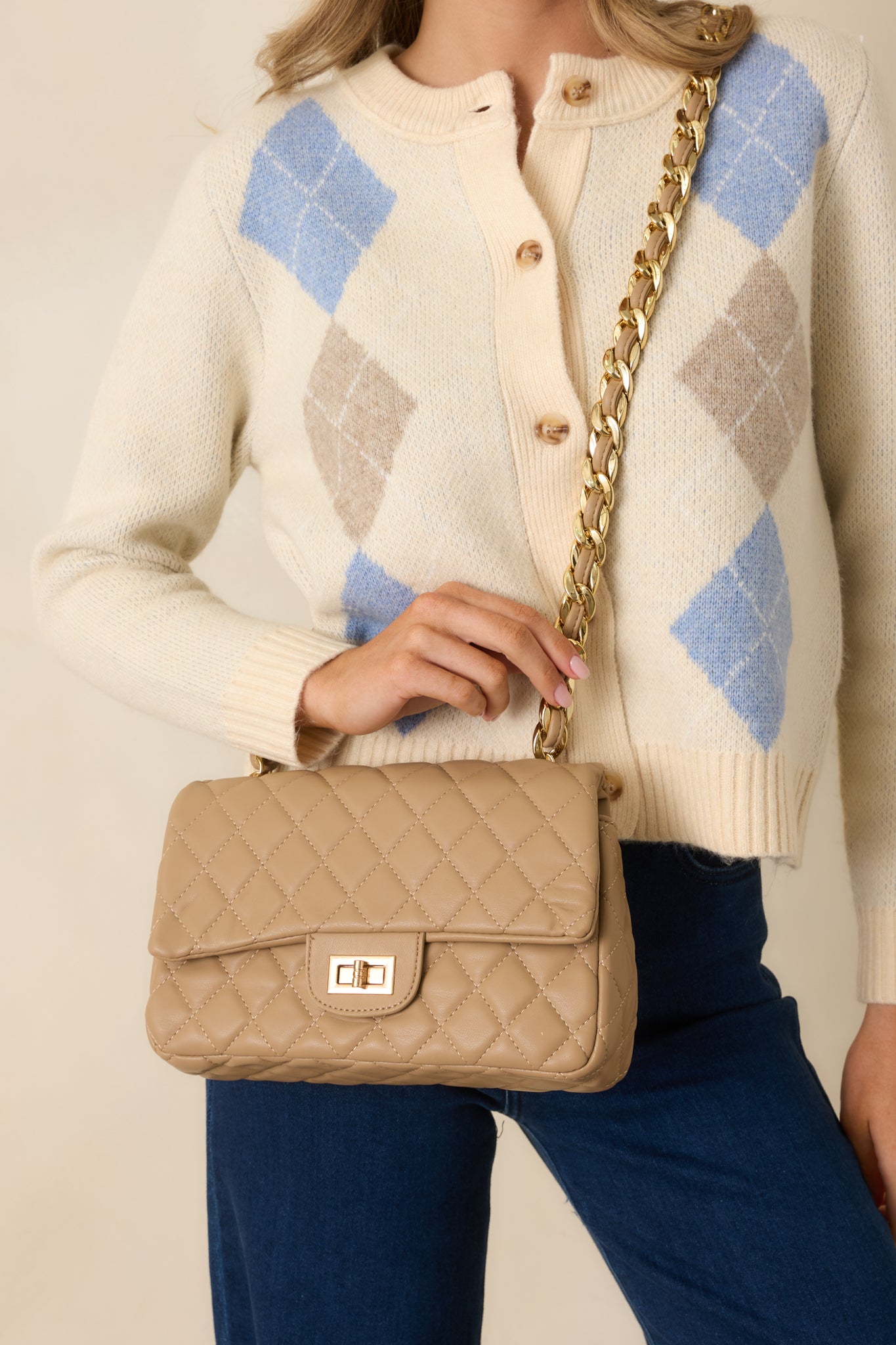 Full view of the taupe quilted handbag featuring gold hardware, a chain strap, and a twist lock closure.