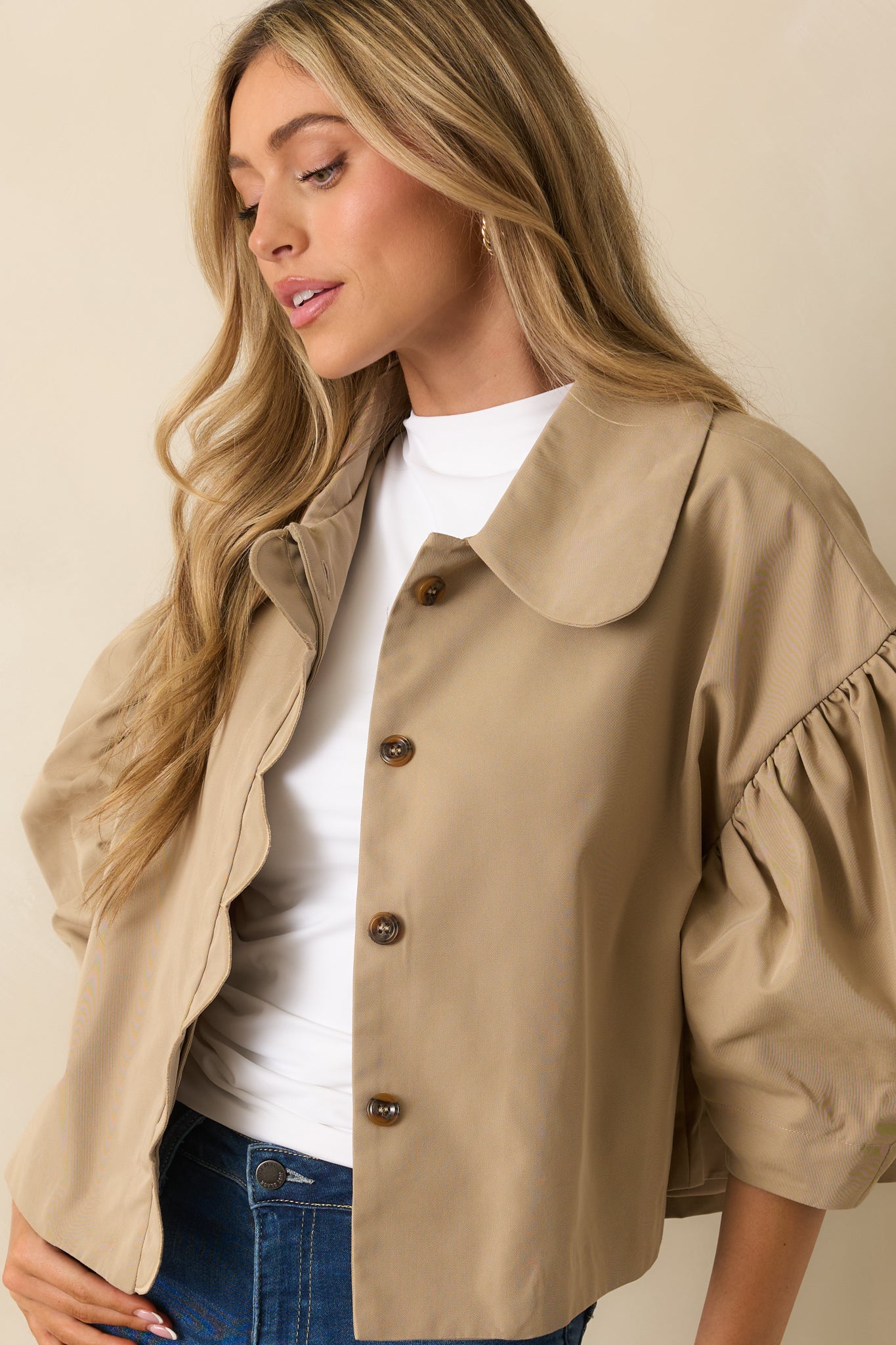 Close crop showing scalloped front placket and button details on taupe woven jacket.