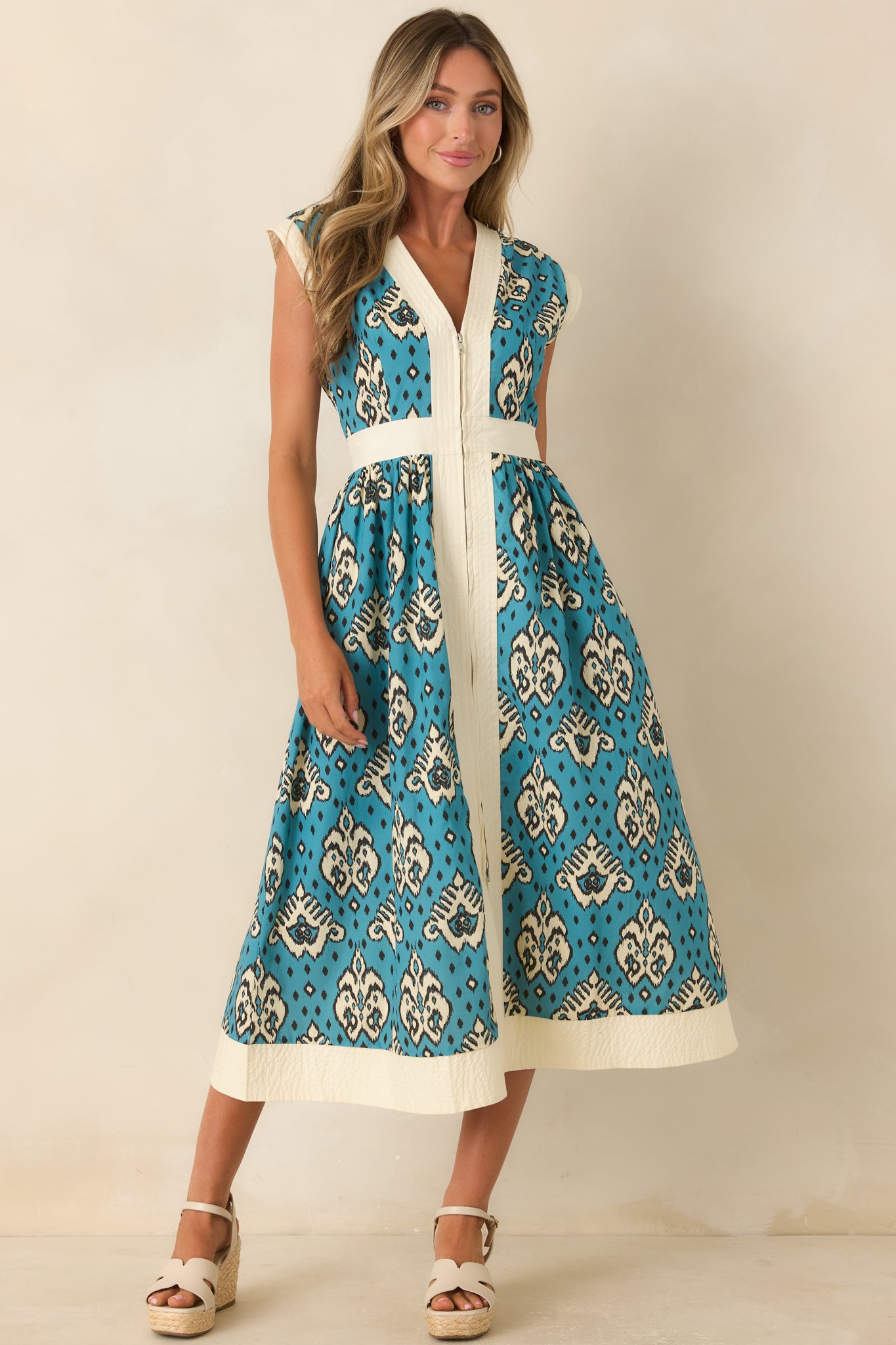 Cotton midi dress designed with a striking teal print, full front zipper, defined waist, and softly flowing skirt.