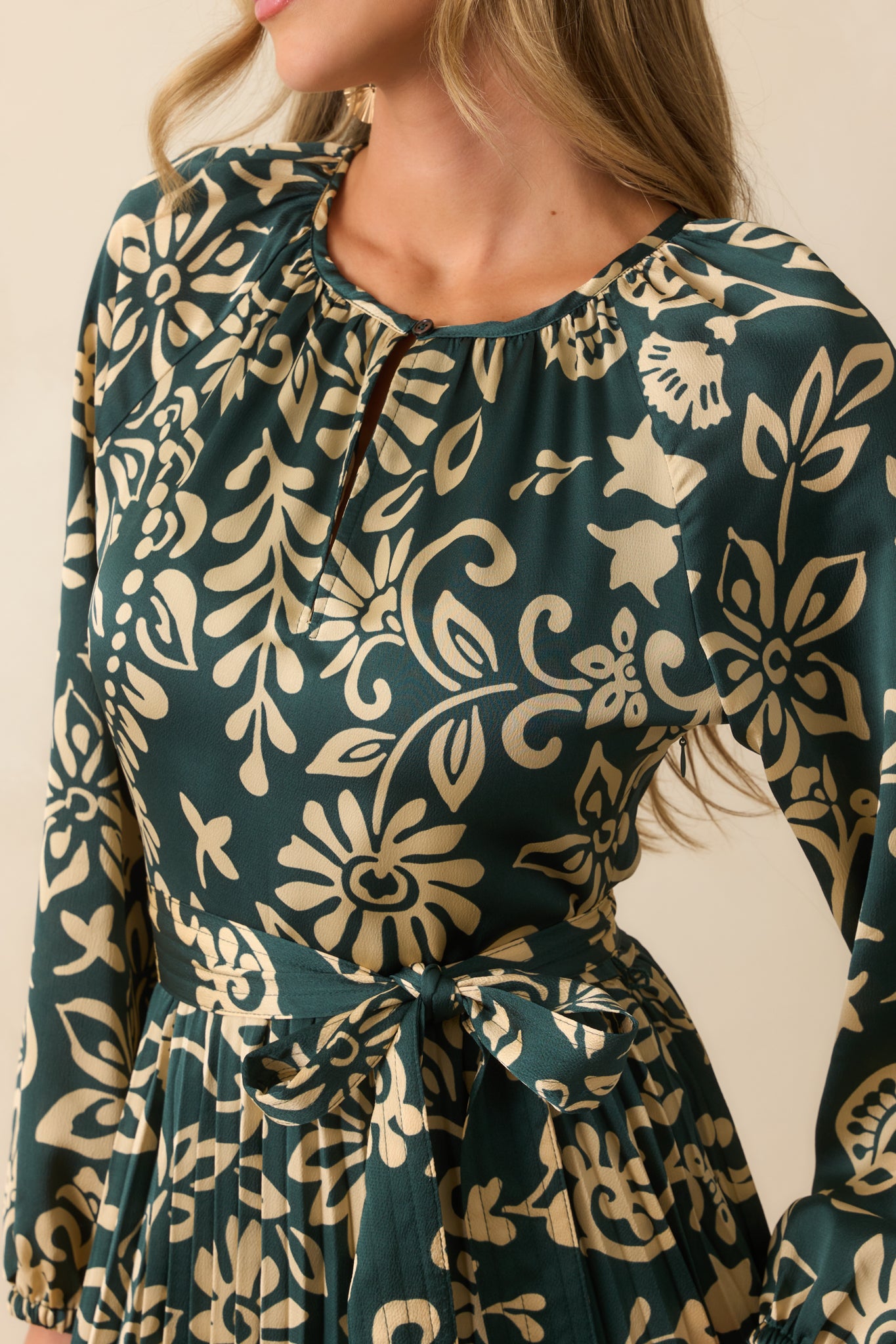 Detailed look at the floral print and pleated fabric texture on the teal dress.