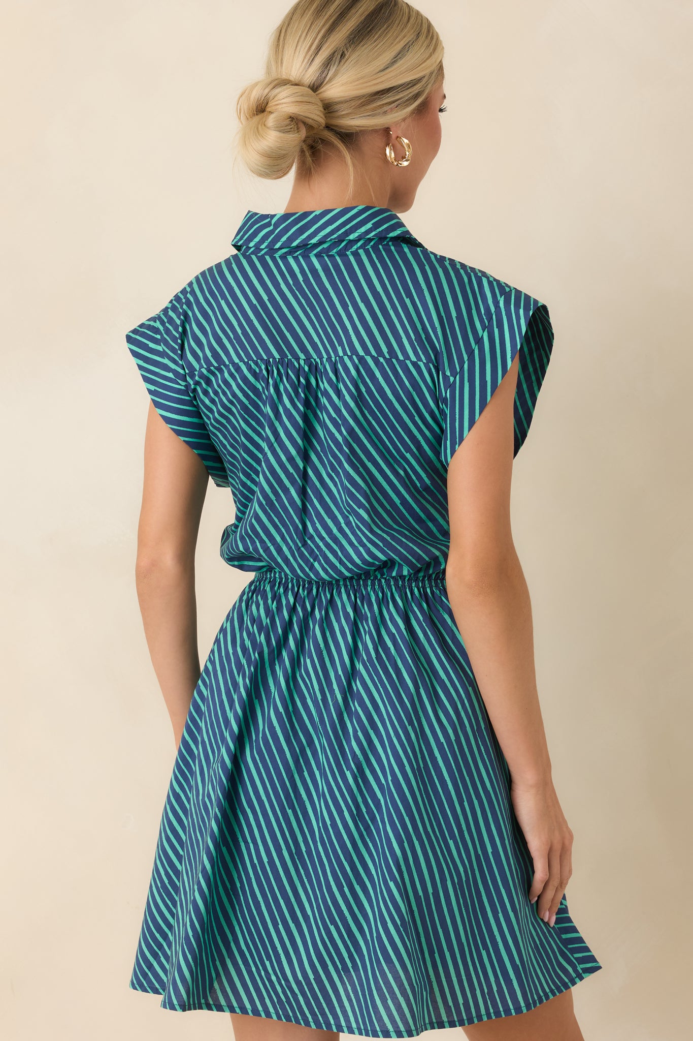 Back view of the teal and navy striped mini dress featuring cap sleeves, a flared skirt, and a clean patterned finish.
