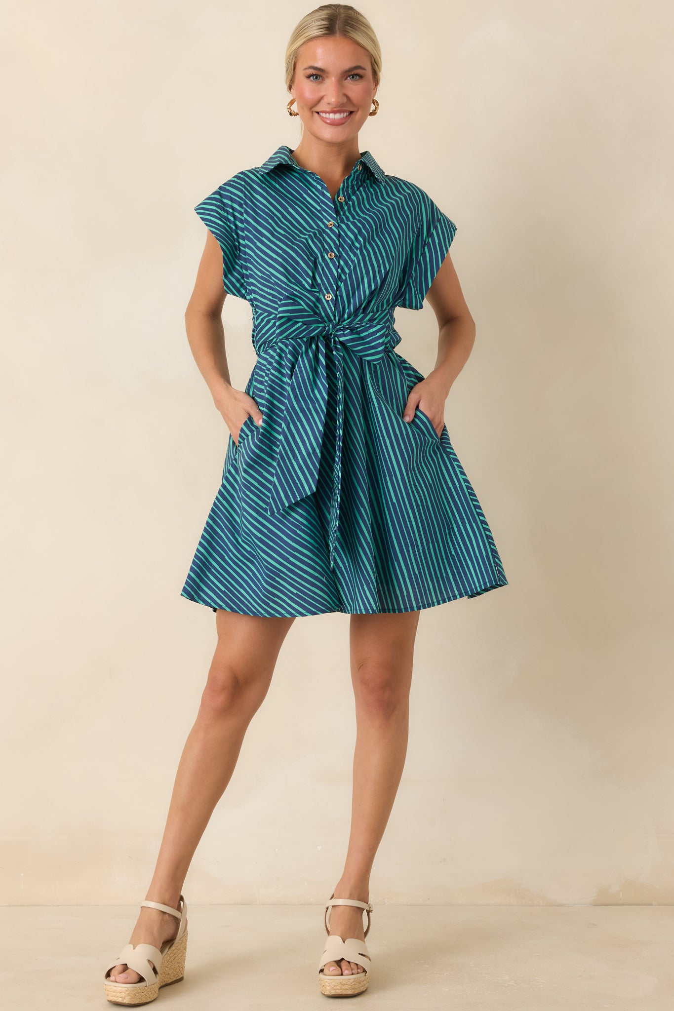 Teal and navy striped mini dress featuring a collared neckline, button-front bodice, cap sleeves, and a self-tie waist detail.