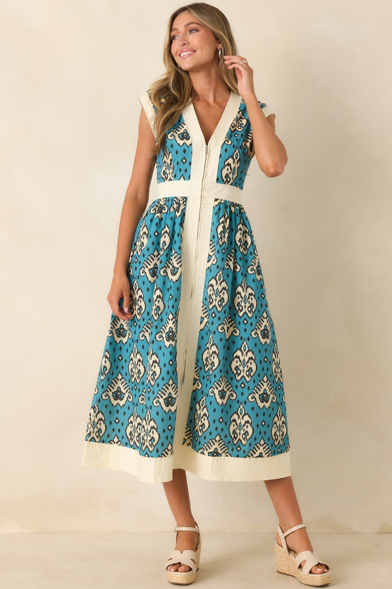 Teal patterned cotton dress with a polished silhouette, V-neckline, contrast trim, and elegant A-line skirt design.