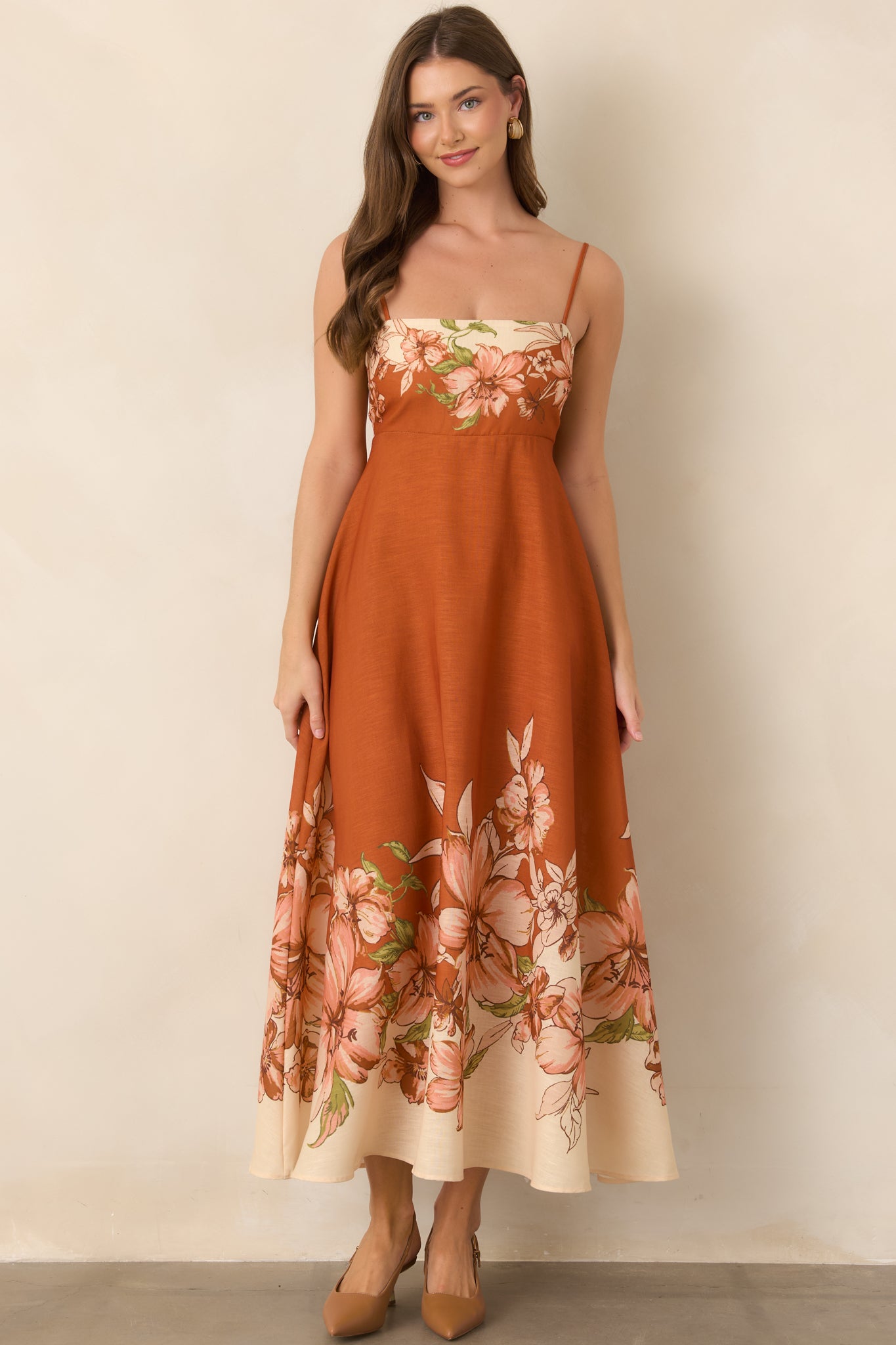 Rich terracotta dress showcasing an ivory, blush, and green floral border print framing the bodice and hem.