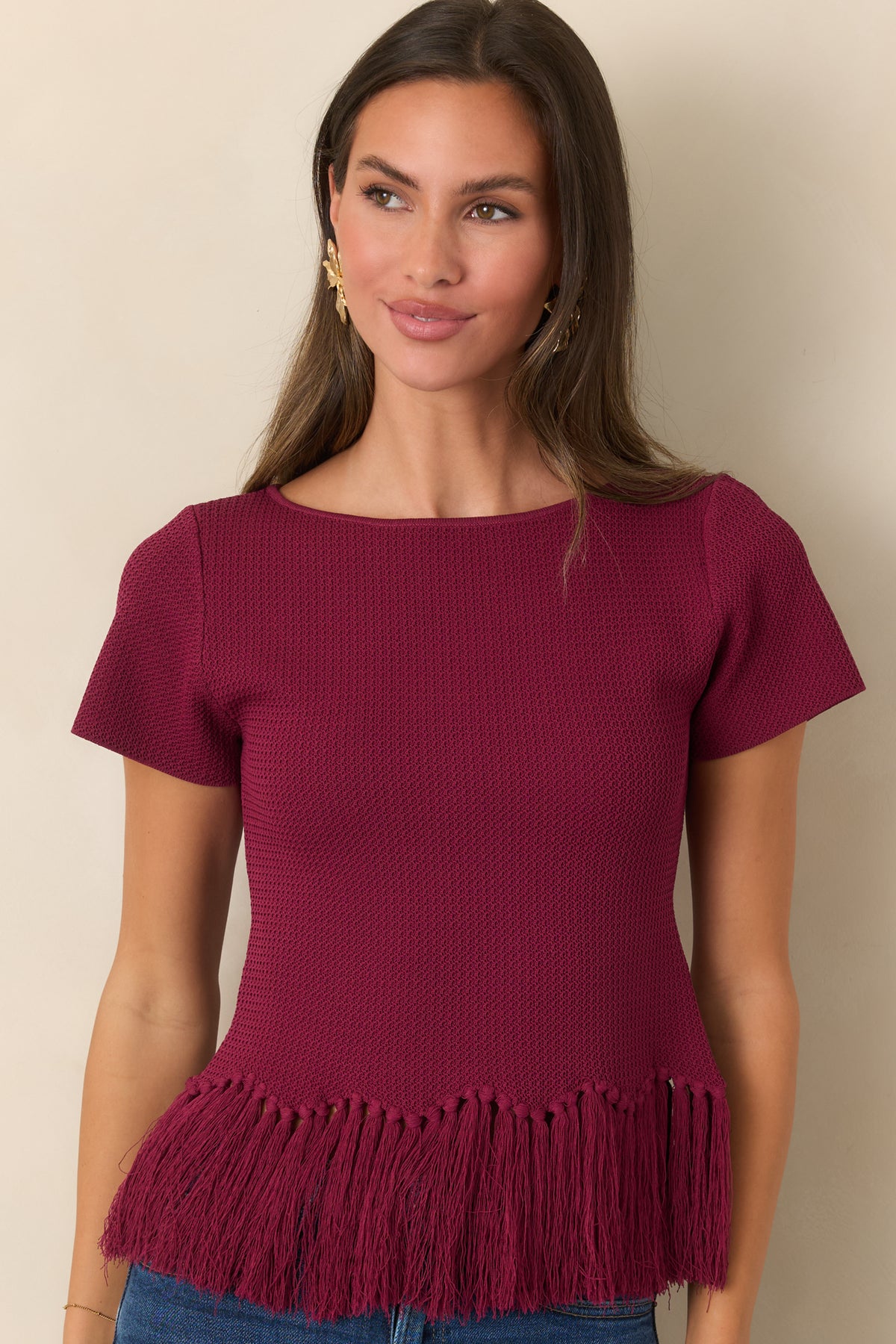 Textured berry knit top finished with short sleeves and a swishy fringe hem.
