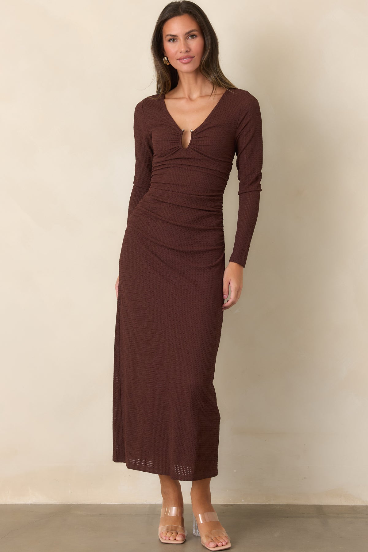 Textured dress highlights the deep V-neckline and ruched waist, flowing into a softly draped midi-length skirt.