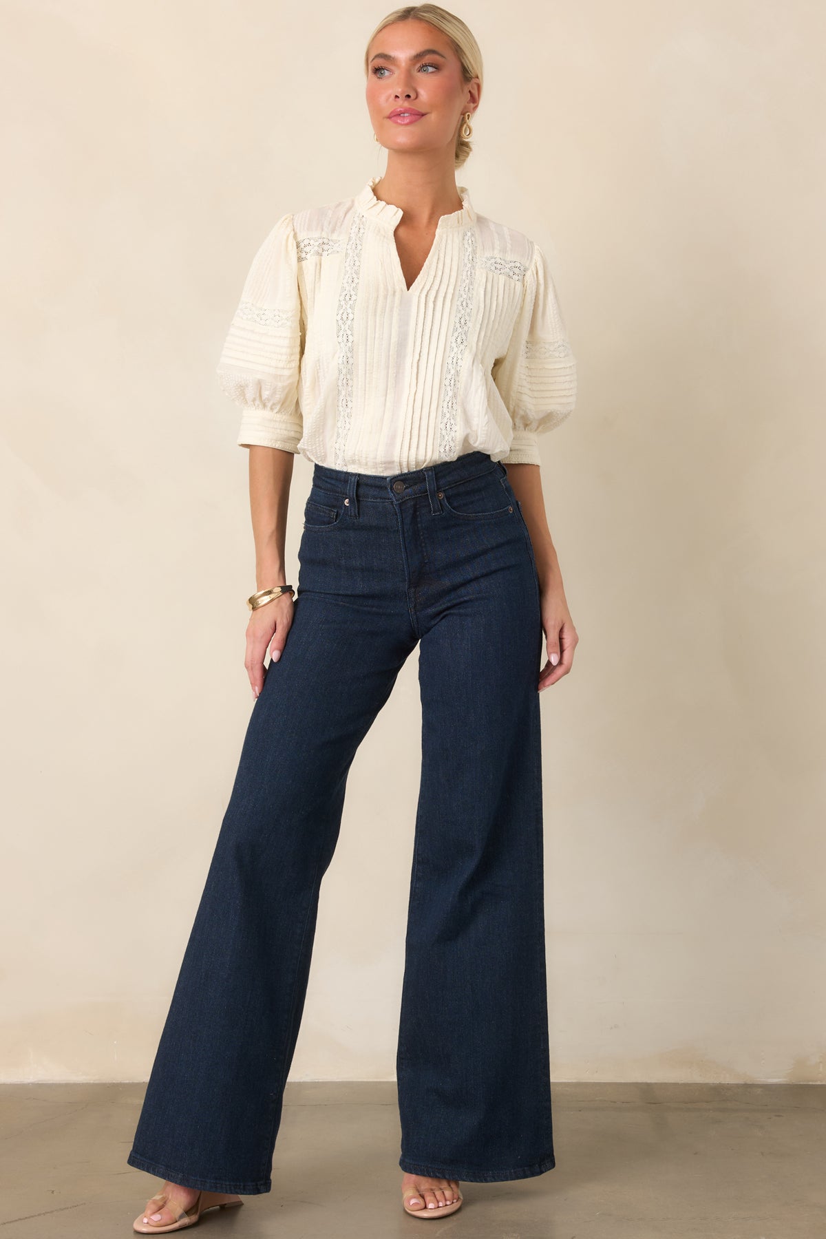 Detailed blouse combining textured fabric with vertical pleats, lace inserts, a feminine ruffled neckline, and airy balloon sleeves.
