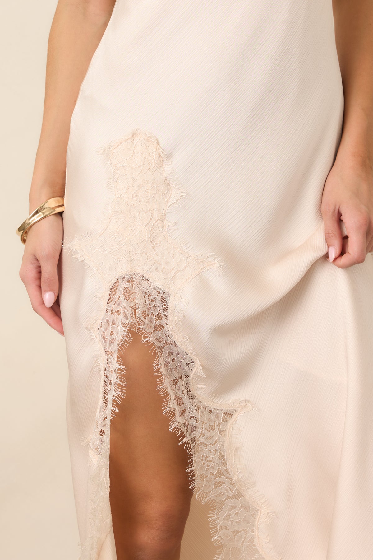 Close view of the textured satin fabric and lace-accented side slit, highlighting the delicate trim and softly draped finish.