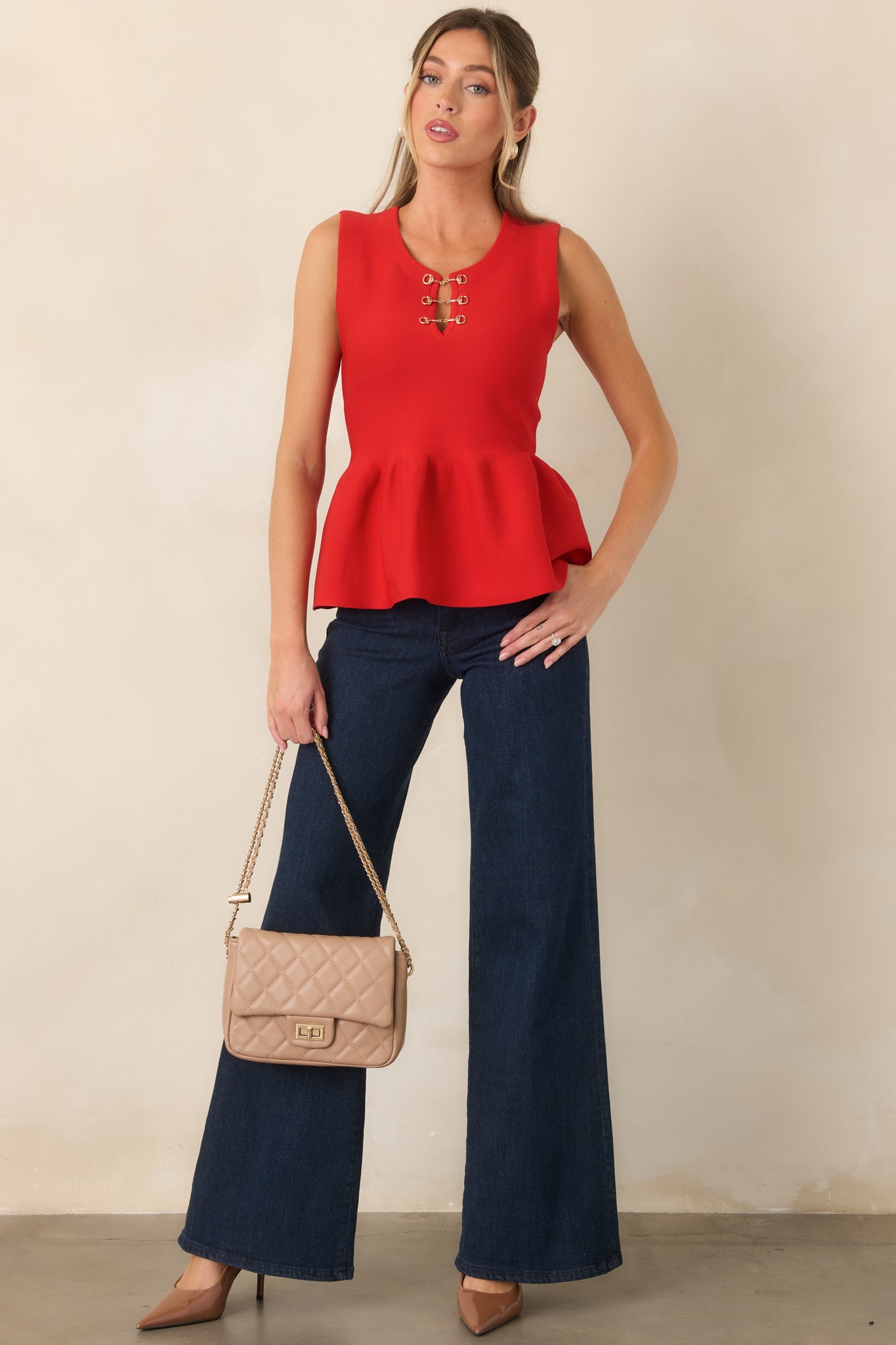 Textured sleeveless top with a contoured fit, waist-defining peplum hem, and distinctive gold-tone neckline hardware for an elevated finish.