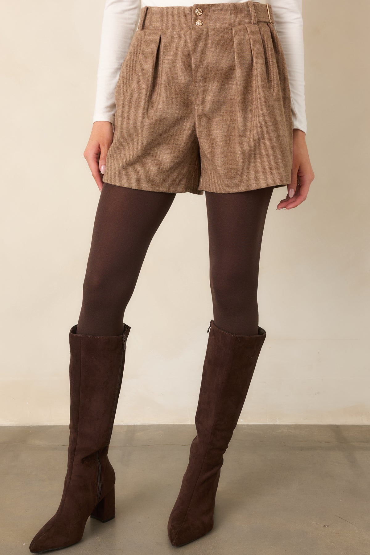 Textured taupe tailoring highlights the front pleats, side buckle details, and spacious leg openings.