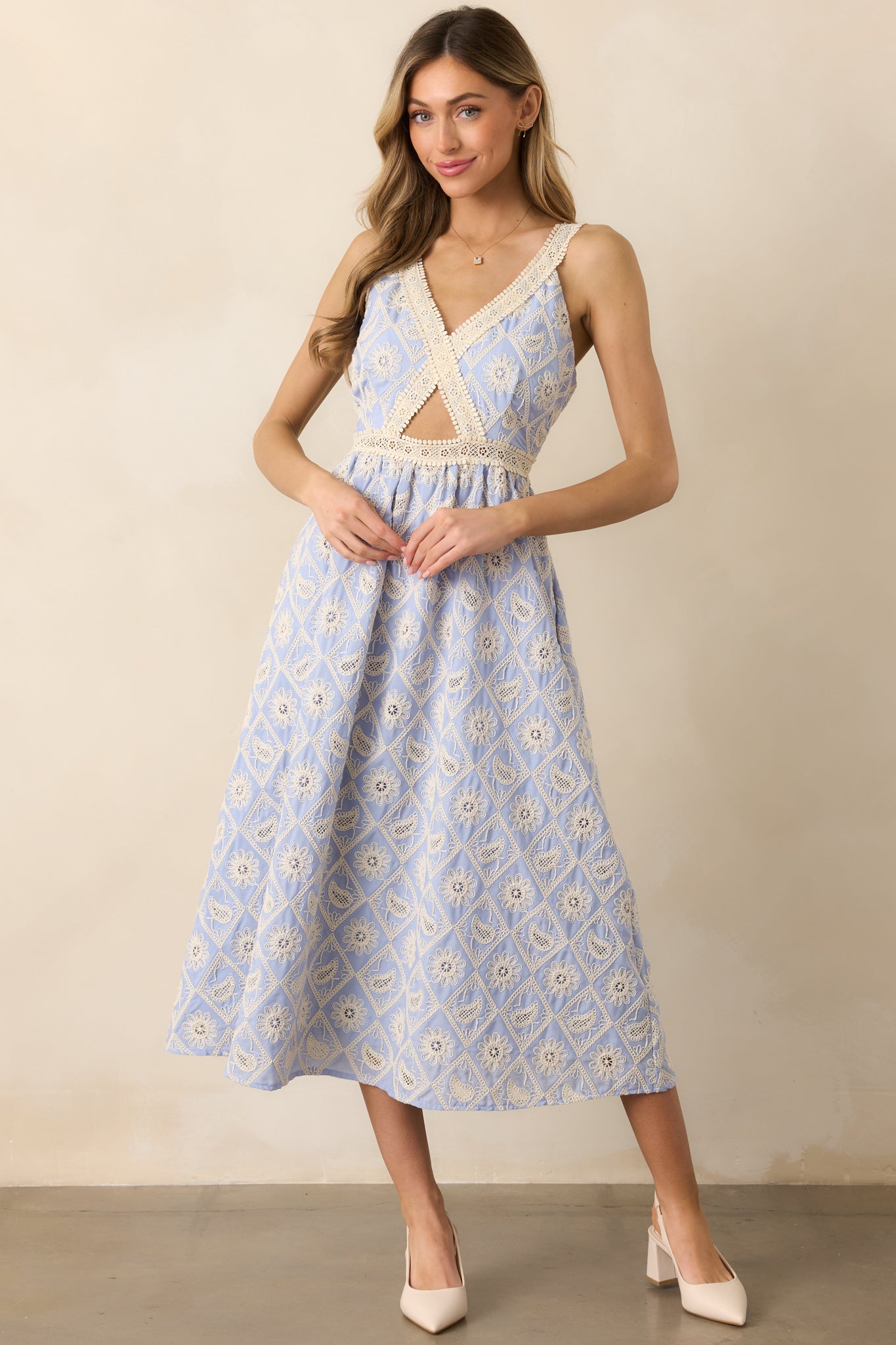 The periwinkle dress features elegant lace embroidery, a v-neckline, and a bodice cutout, with adjustable straps to enhance the dress's feminine silhouette.