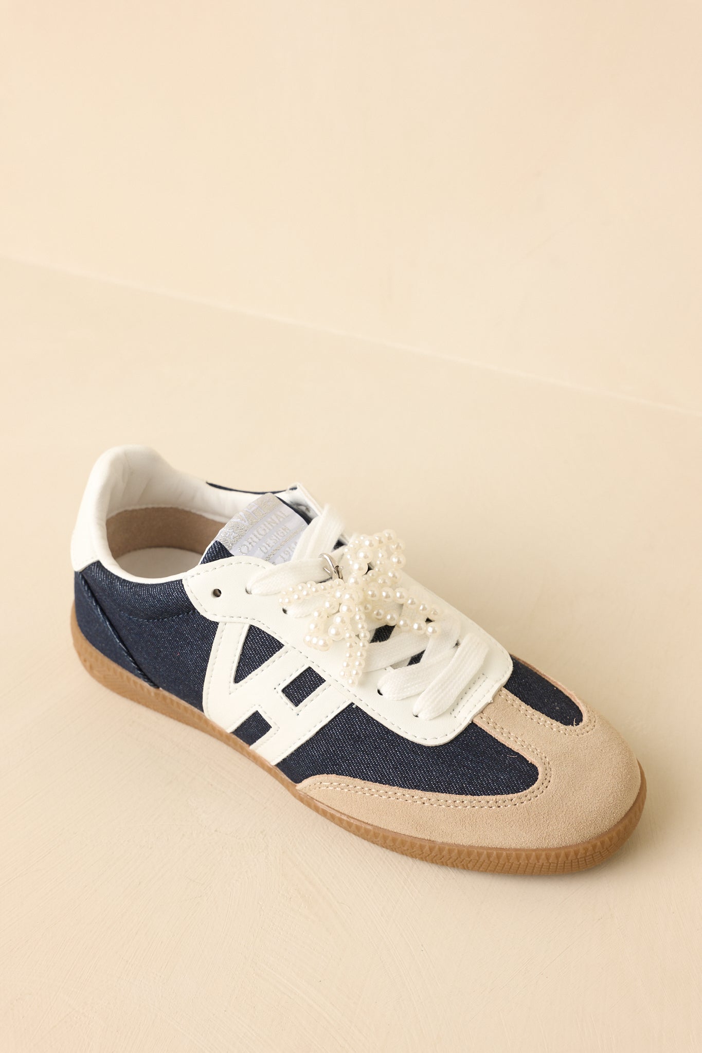 Three-quarter angle showcasing removable pearl bow accent and signature sneaker silhouette.