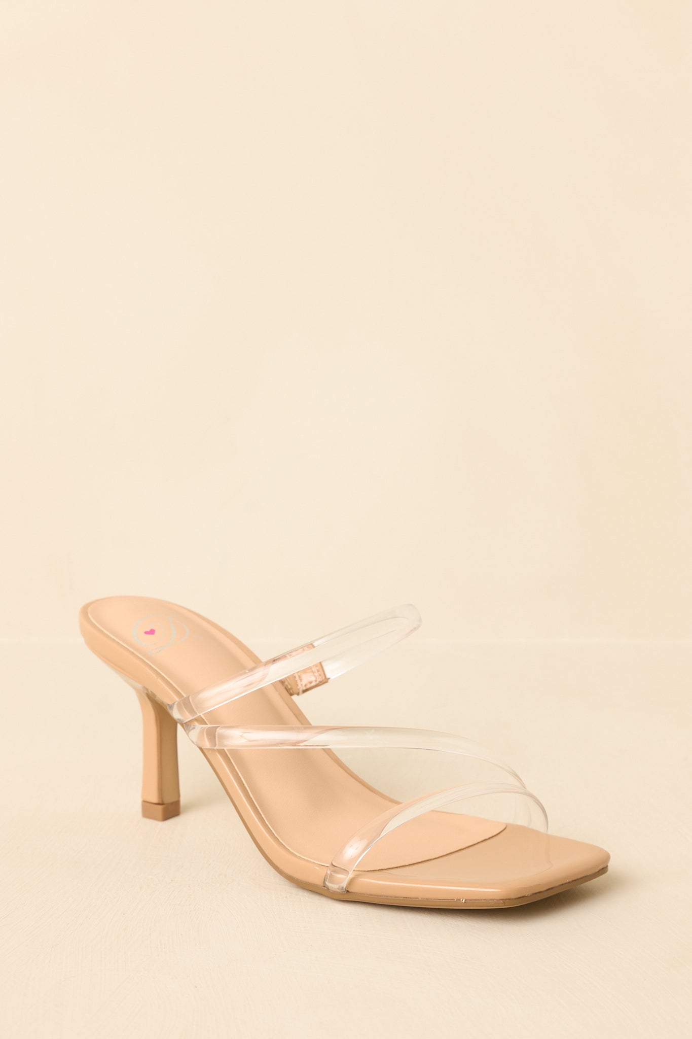 Three-quarter side-back view of nude heels showing heel shape and sleek strap detailing on beige background.