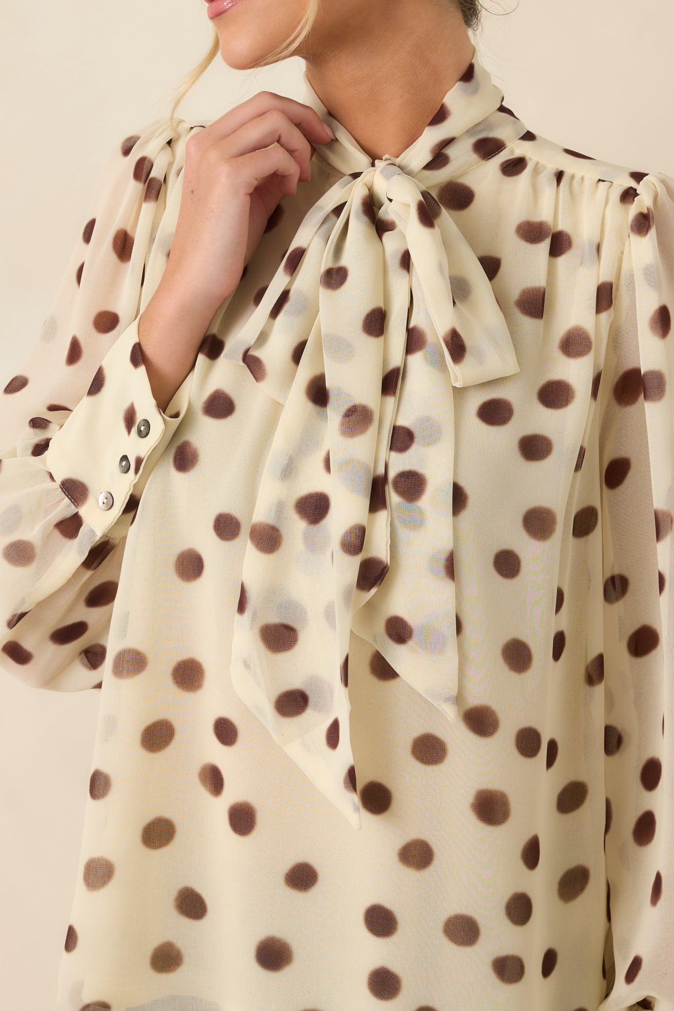 Close-up of the blouse highlighting the self-tie neckline, soft chiffon texture, and painterly polka dot design.