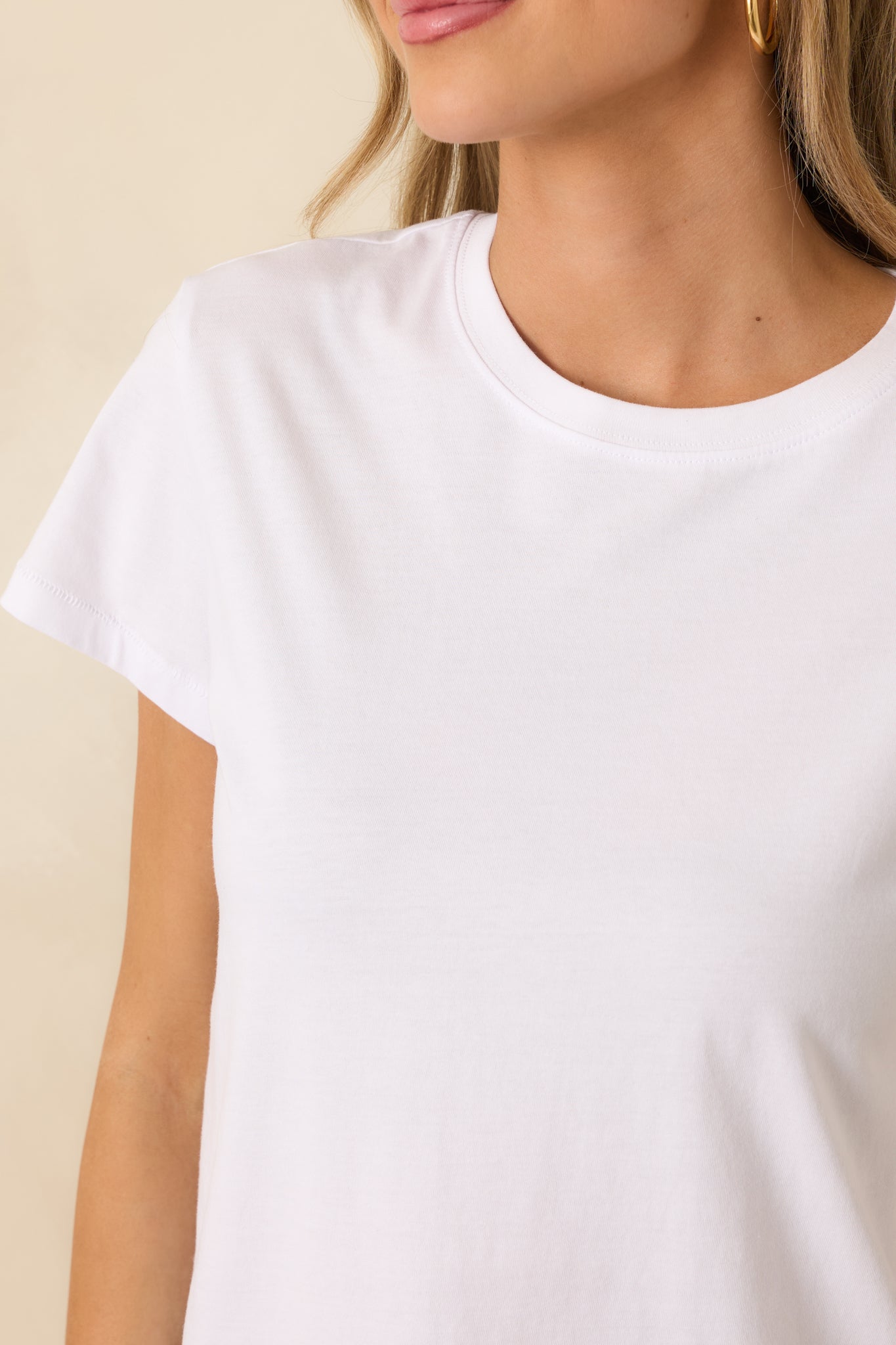 Tight detail of the white cotton knit texture and neckline stitching, showing soft, lightweight construction.