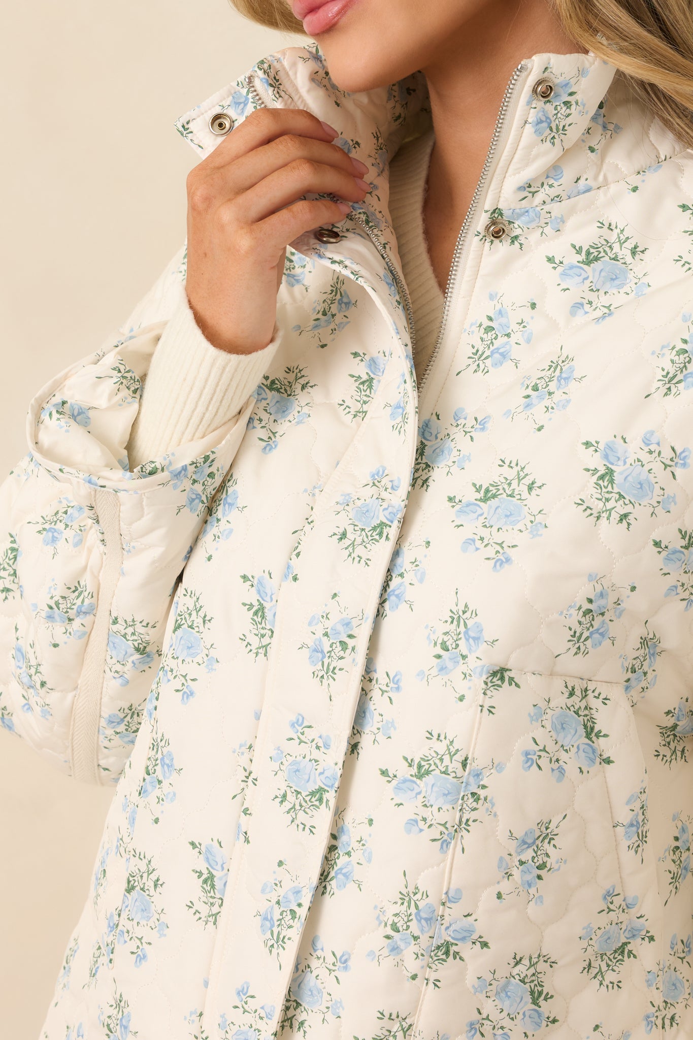 Tight view of the ivory jacket fabric showcasing the blue floral pattern, subtle green accents, and quilted stitching.
