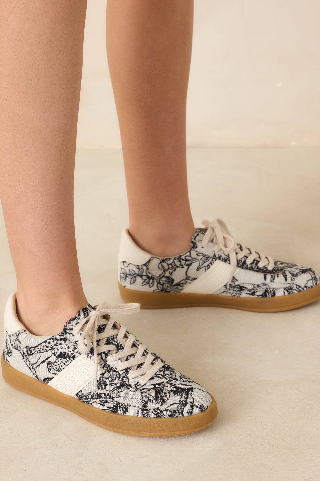 Top-down angle of ivory sneakers displaying lace-up detailing and cream faux leather accents.
