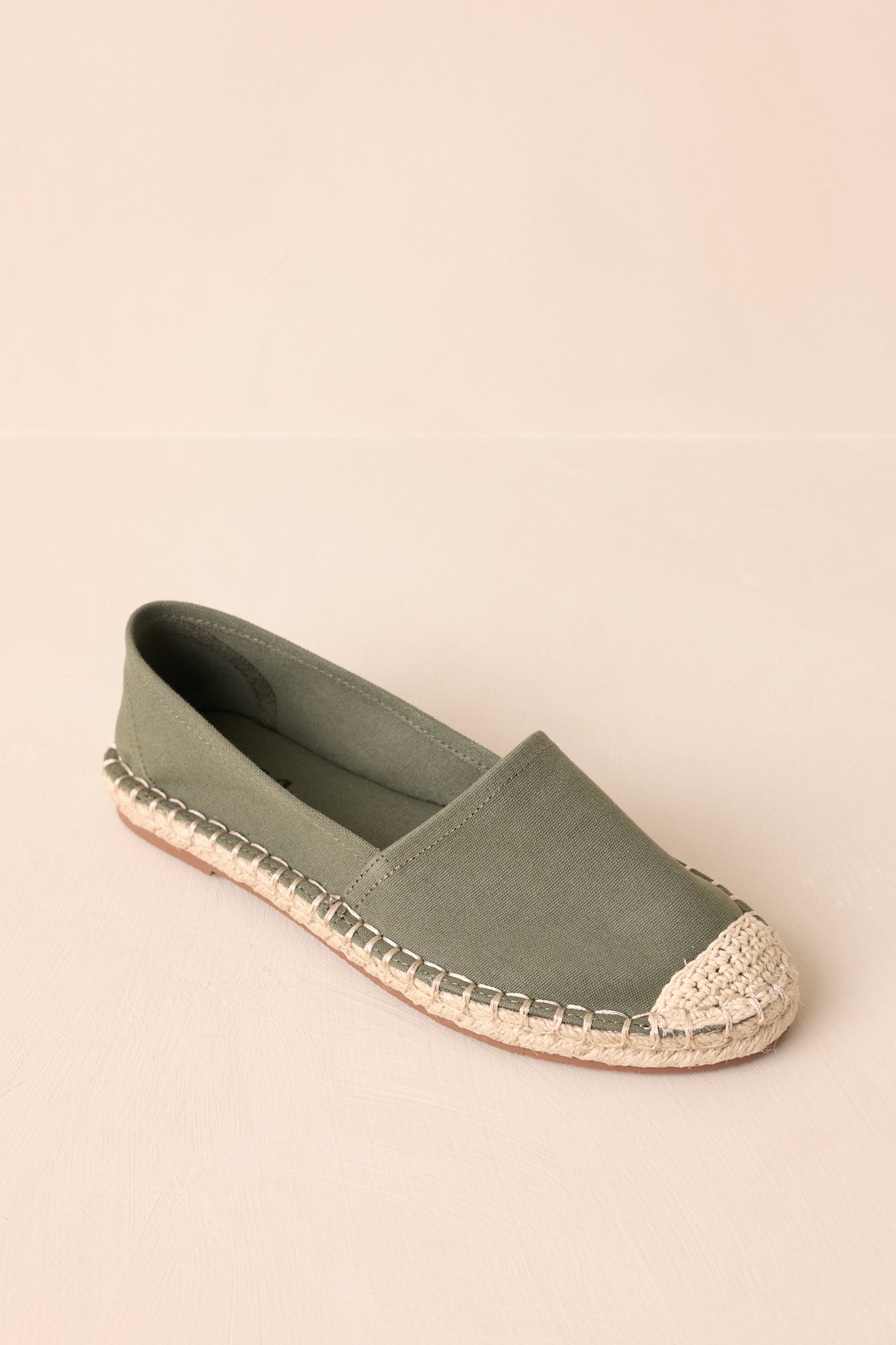 A top-down view of the earthy green flat shoes highlighting the canvas texture and shape of the round toe.