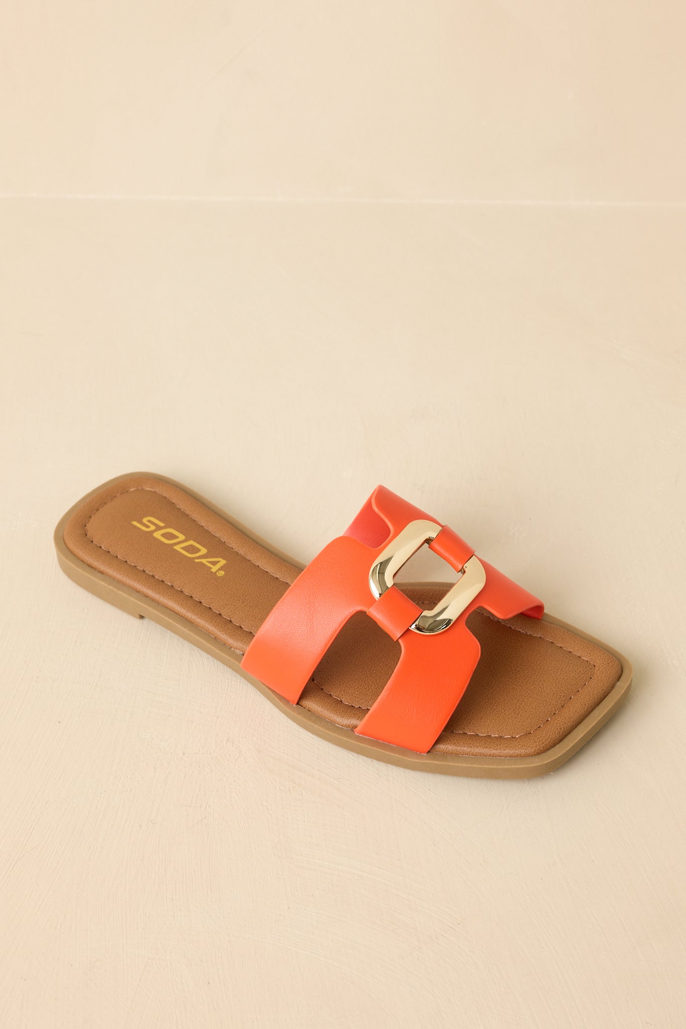 Top-down view of the orange slide sandals against a beige background showcasing the square toe and smooth strap surface.