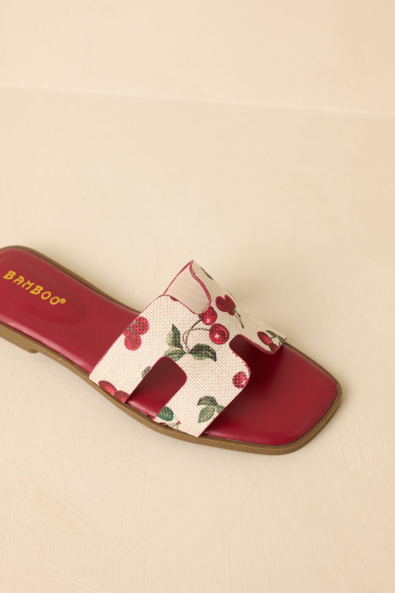 Top-down view of slide sandals on beige background showing vibrant fruit print strap and open toe