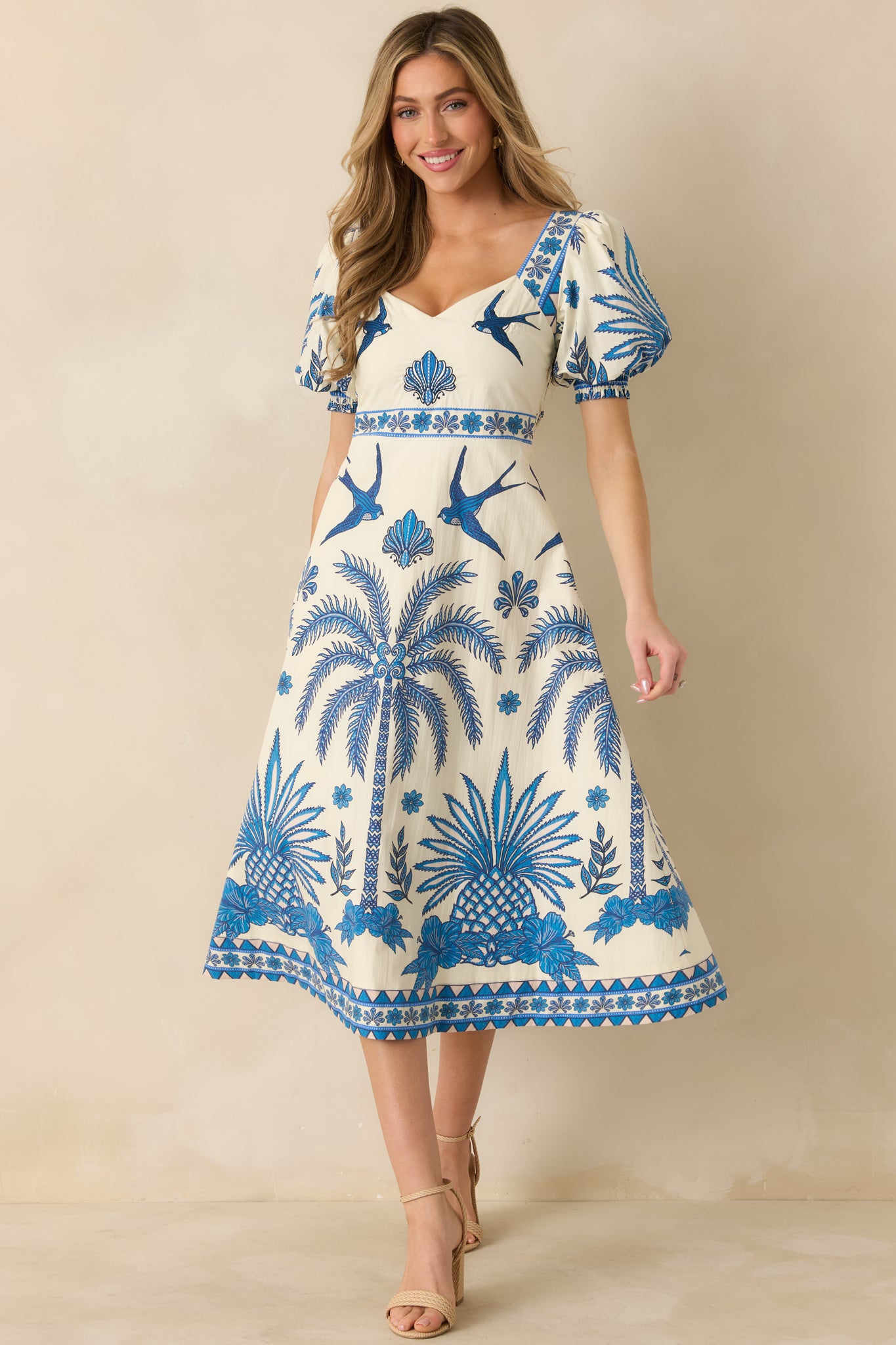 Blue and ivory tropical print midi dress shown front-facing with puff sleeves and flowing skirt.