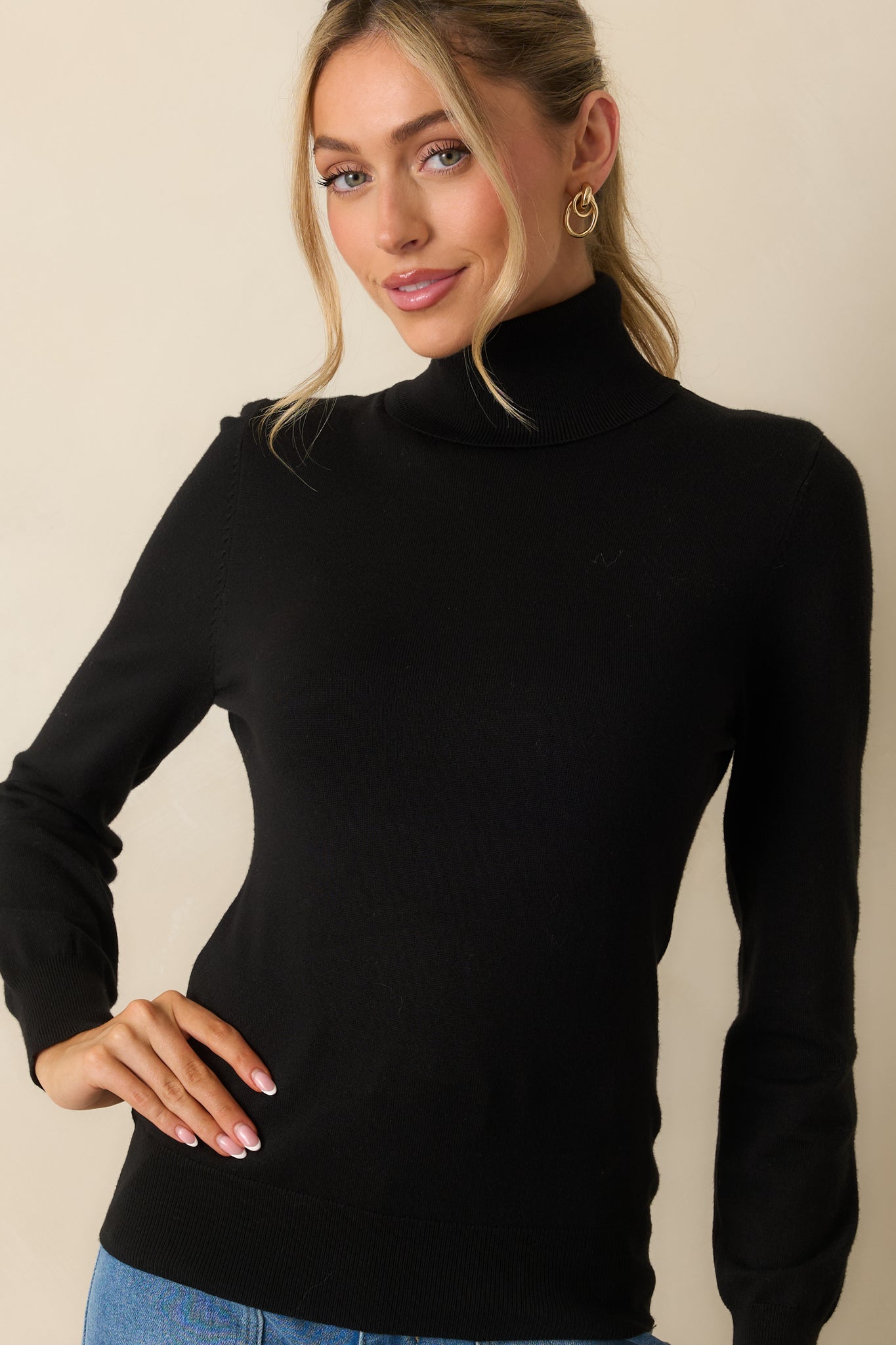 Turtleneck sweater in soft black knit showing fine ribbed edges and smooth construction.