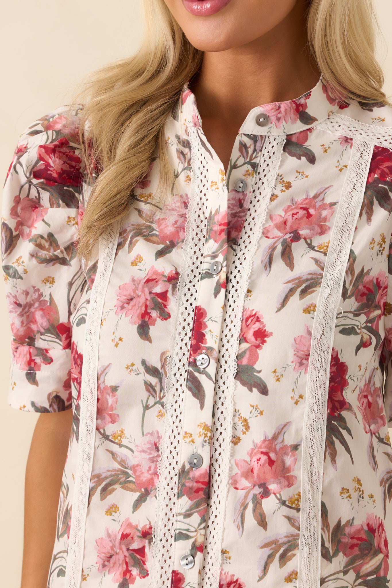 Close-up detail of the lace trim panel and button detailing on the pink floral top.