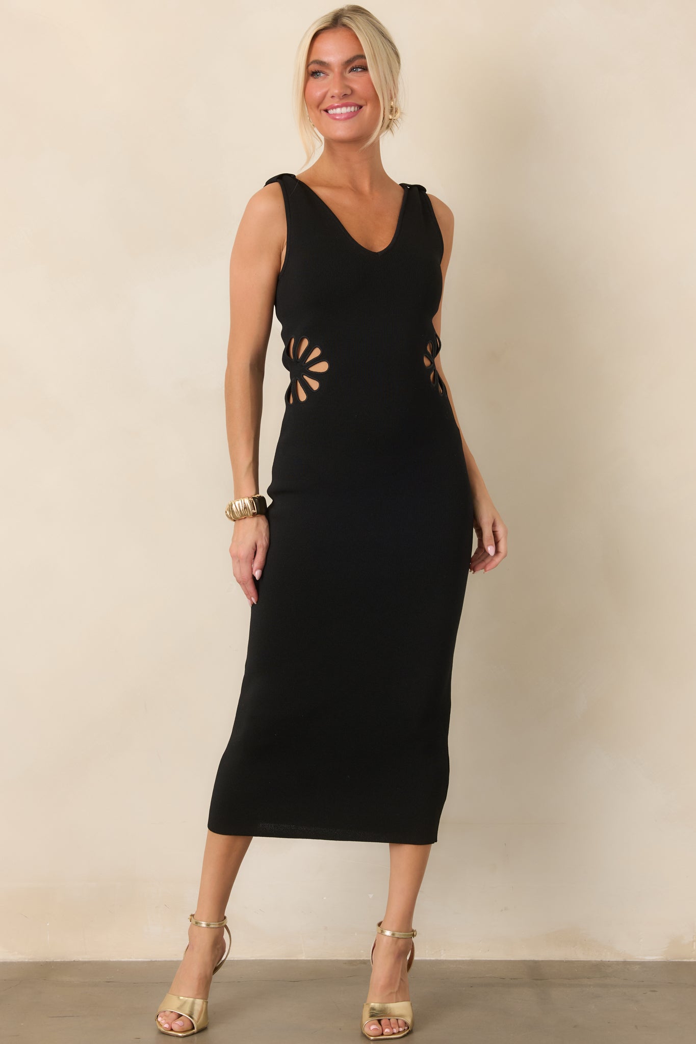 Body-skimming knit dress with a sleek V-neck, broad straps, and decorative floral-shaped cutouts accenting the waist.