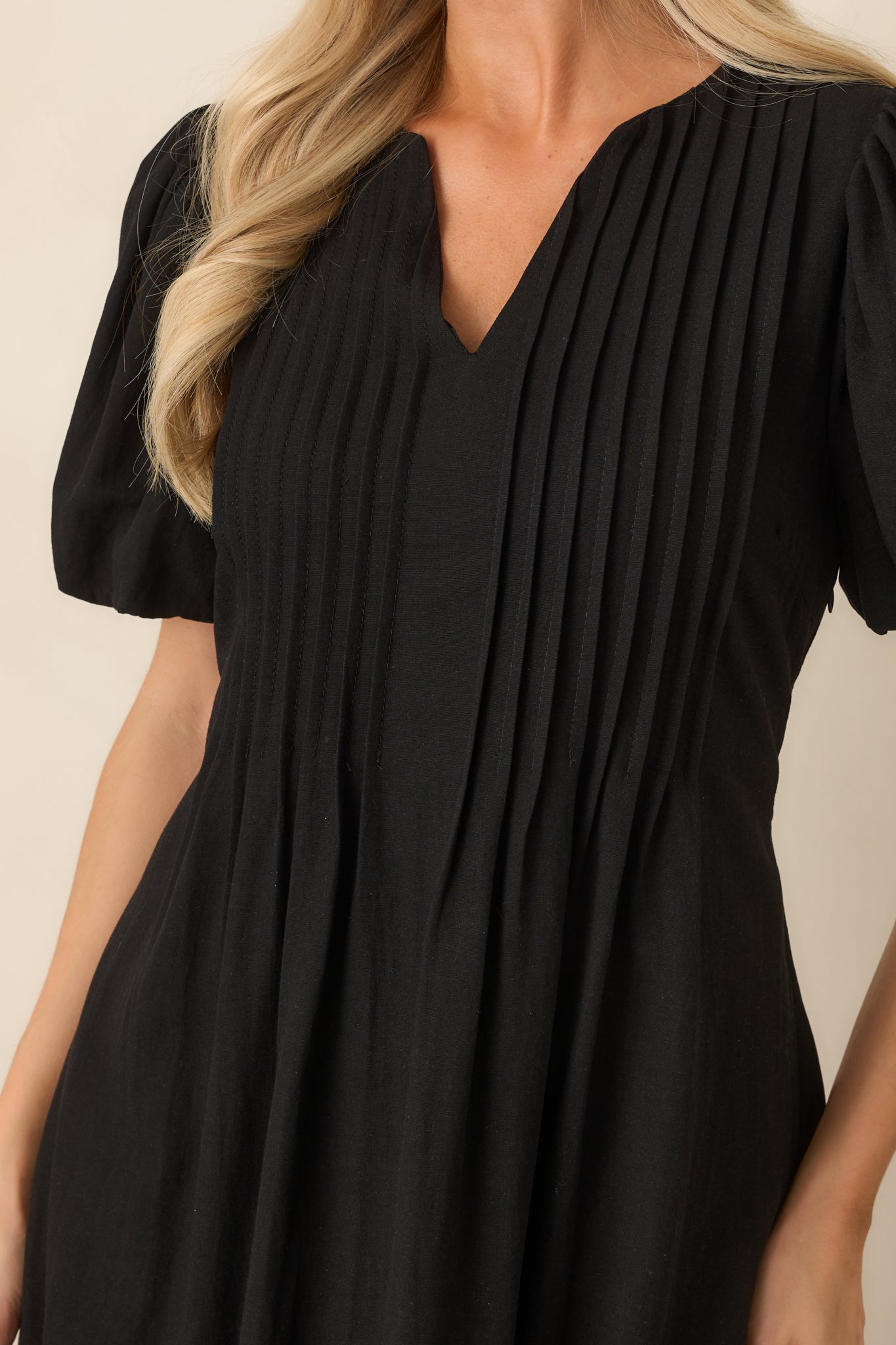 Close-up of the V-neckline and pintuck detailing, highlighting the linen-like texture and softly gathered puff sleeve construction.