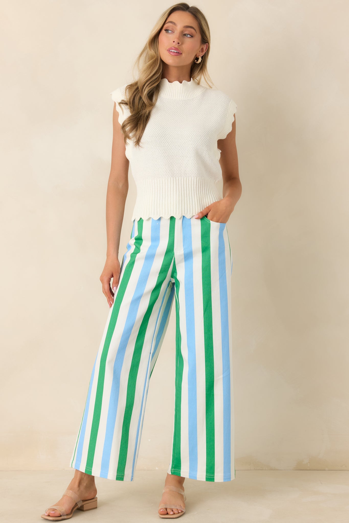 Green, blue, and white vertically striped pants with a high-rise waist, wide leg silhouette, front pockets, and zipper button closure.