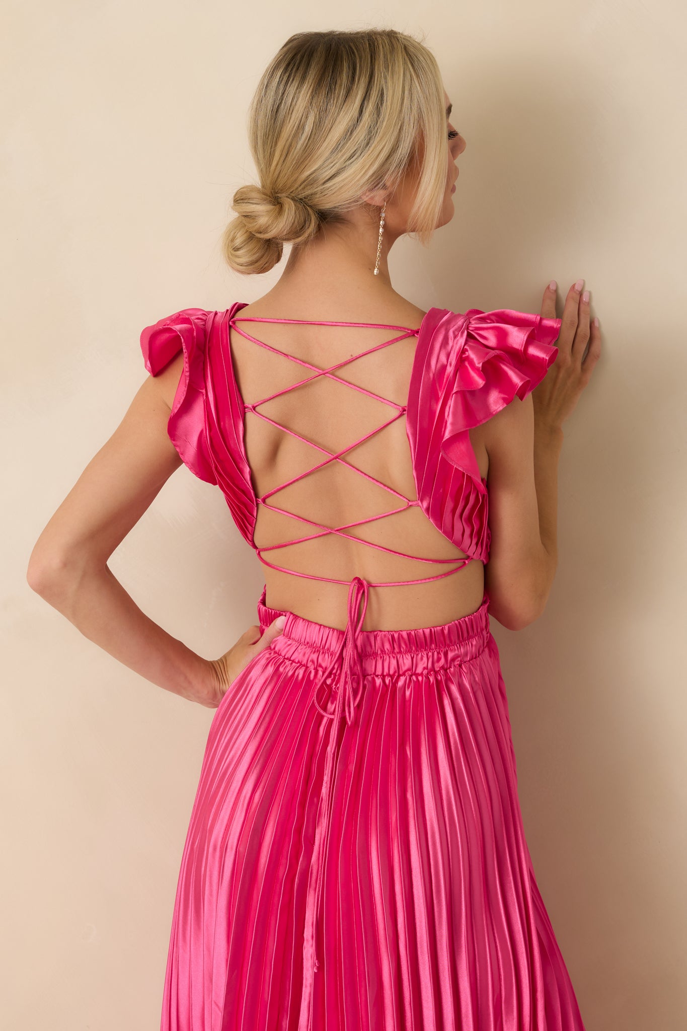 View from behind showing lace-up closure, elasticized waistband, and flowing pleated maxi skirt.