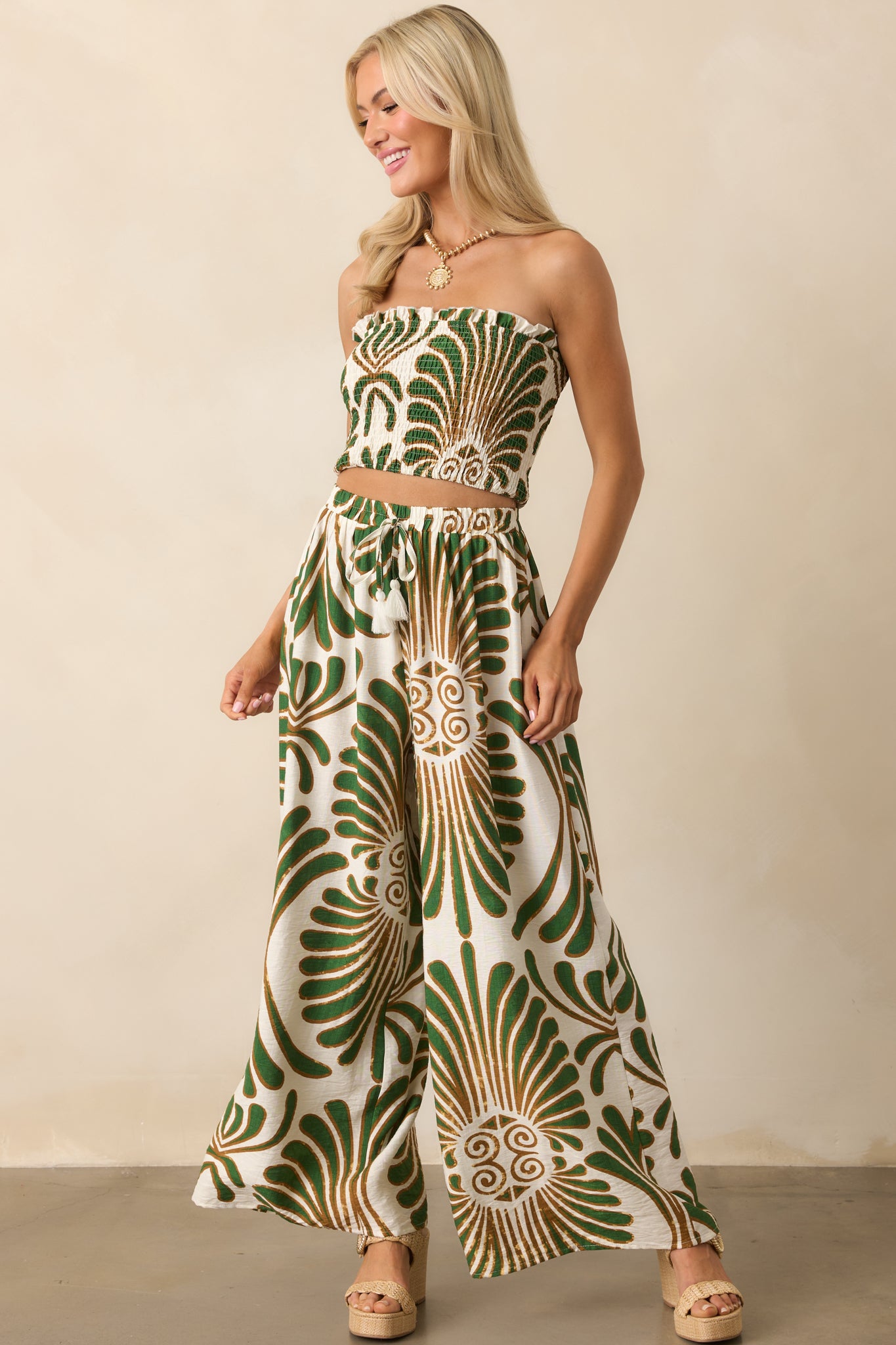 Full body angled view highlighting the adjustable drawstring with ivory fringe tassels and the relaxed drape of the wide legs.