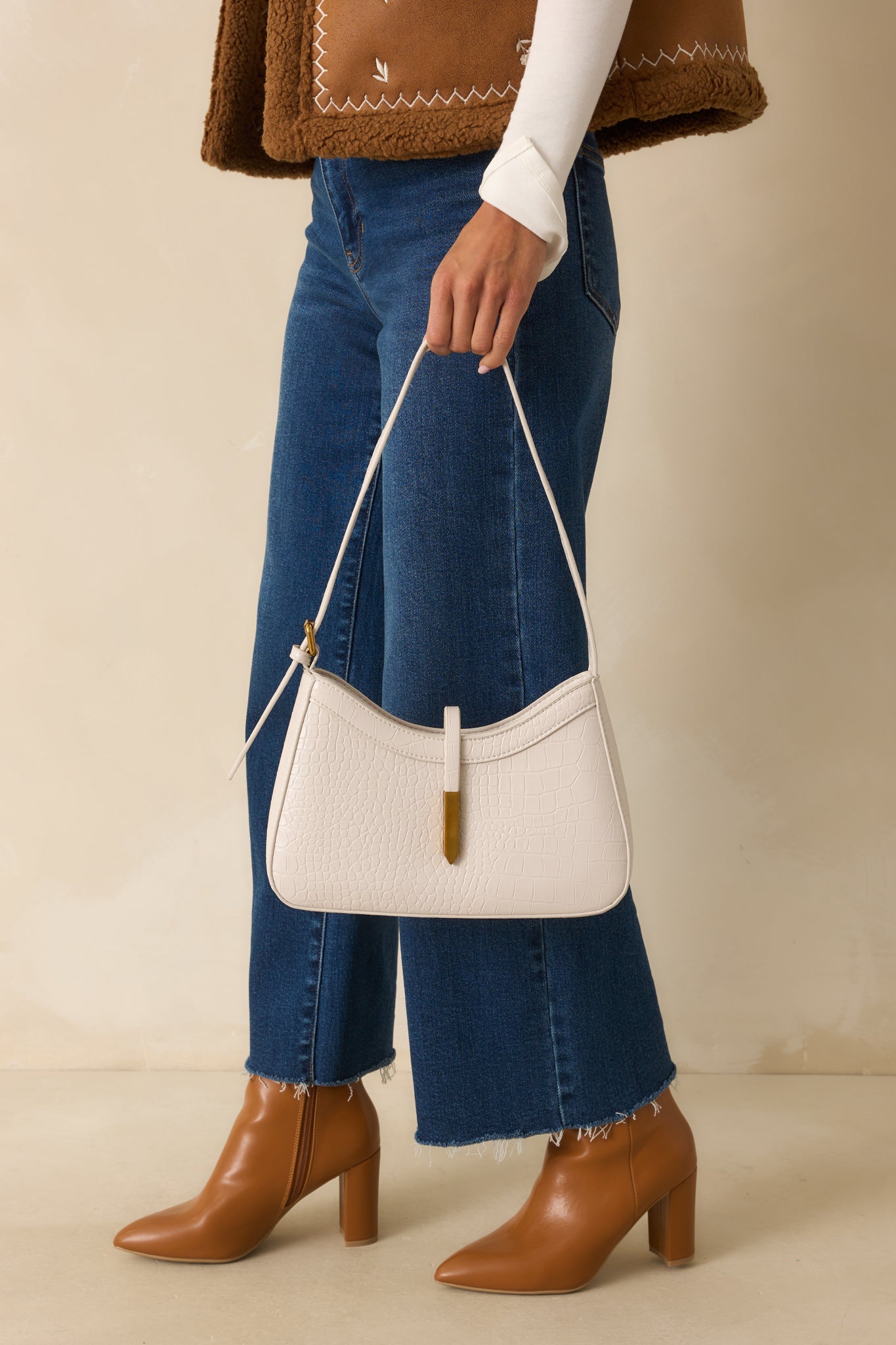 Cropped view highlighting the single strap closure with rectangular brushed gold tip and polished hardware.