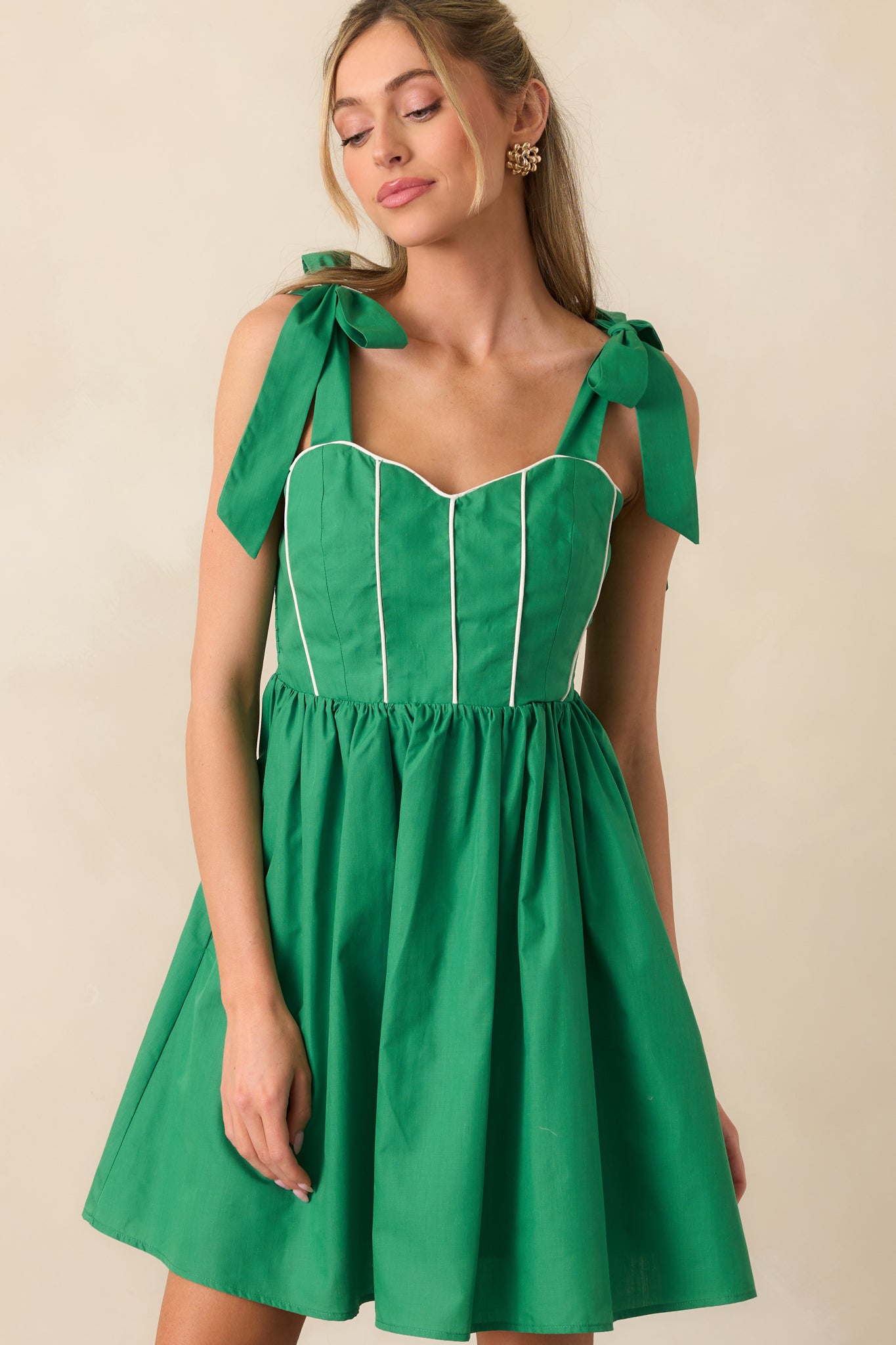 Zoomed-in view of bow-tied straps on the green mini dress, showing adjustable self-tie detail at the shoulder.