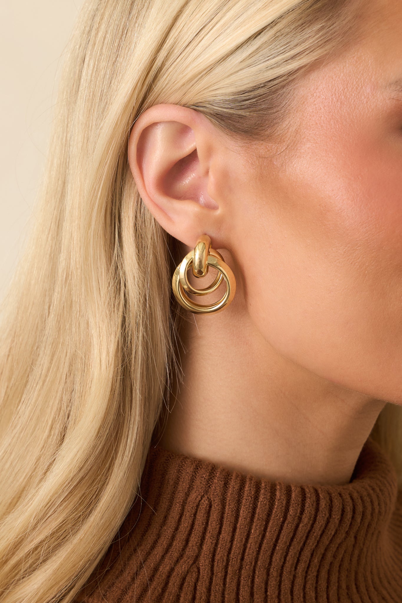 Cropped view of gold-tone earrings with an interlocking circle drop design and smooth polished finish.
