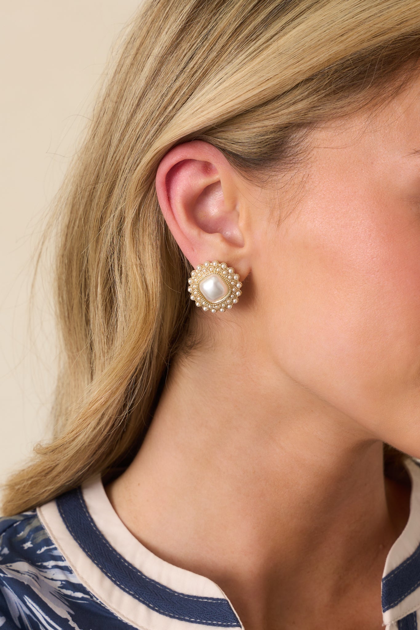 Cropped view of the medium-sized gold circle earrings with a square faux ivory pearl center and textured gold hardware.