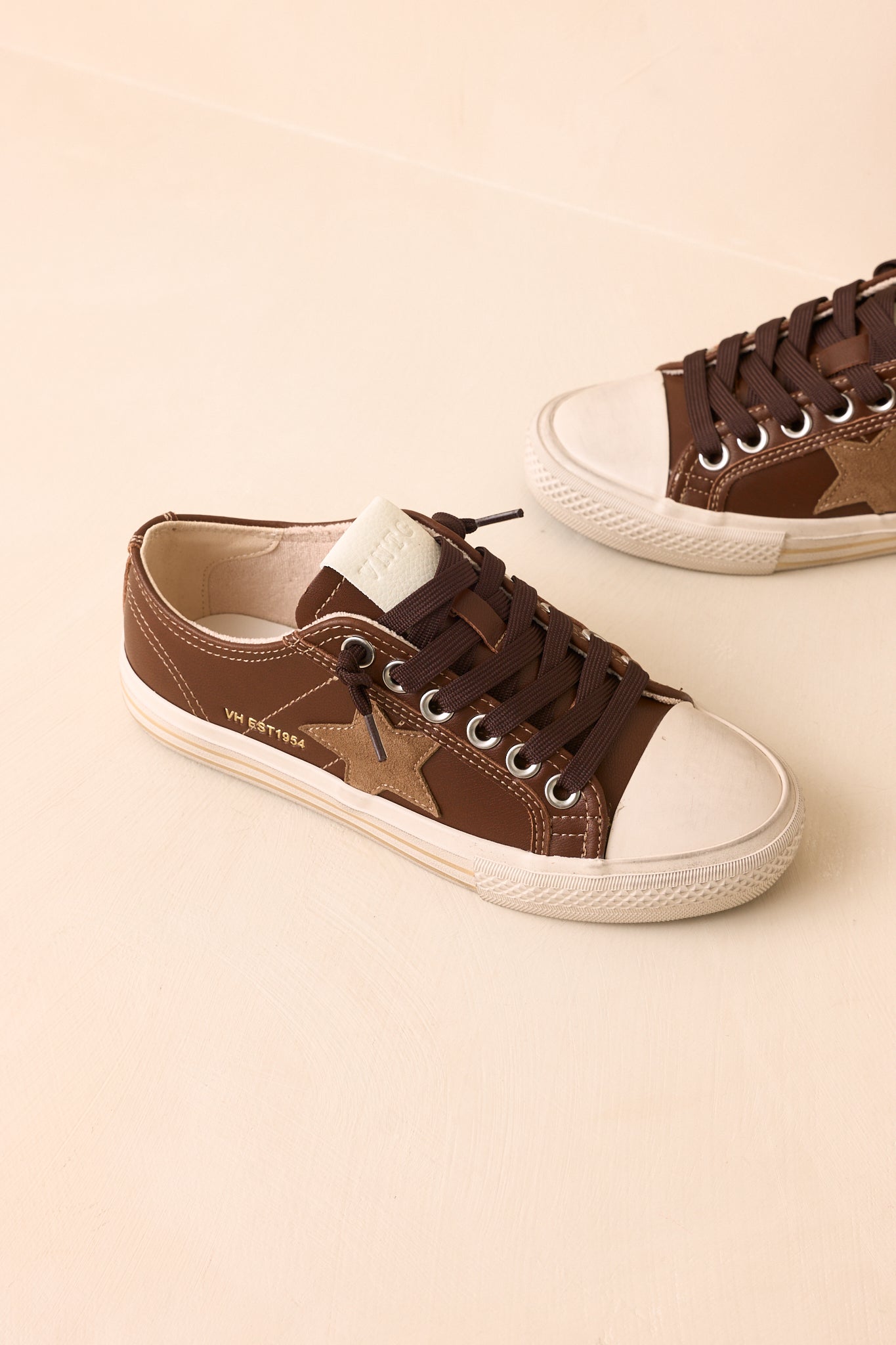 Vintage-inspired sneakers crafted from leather, suede, and canvas with dark brown laces and layered soles.