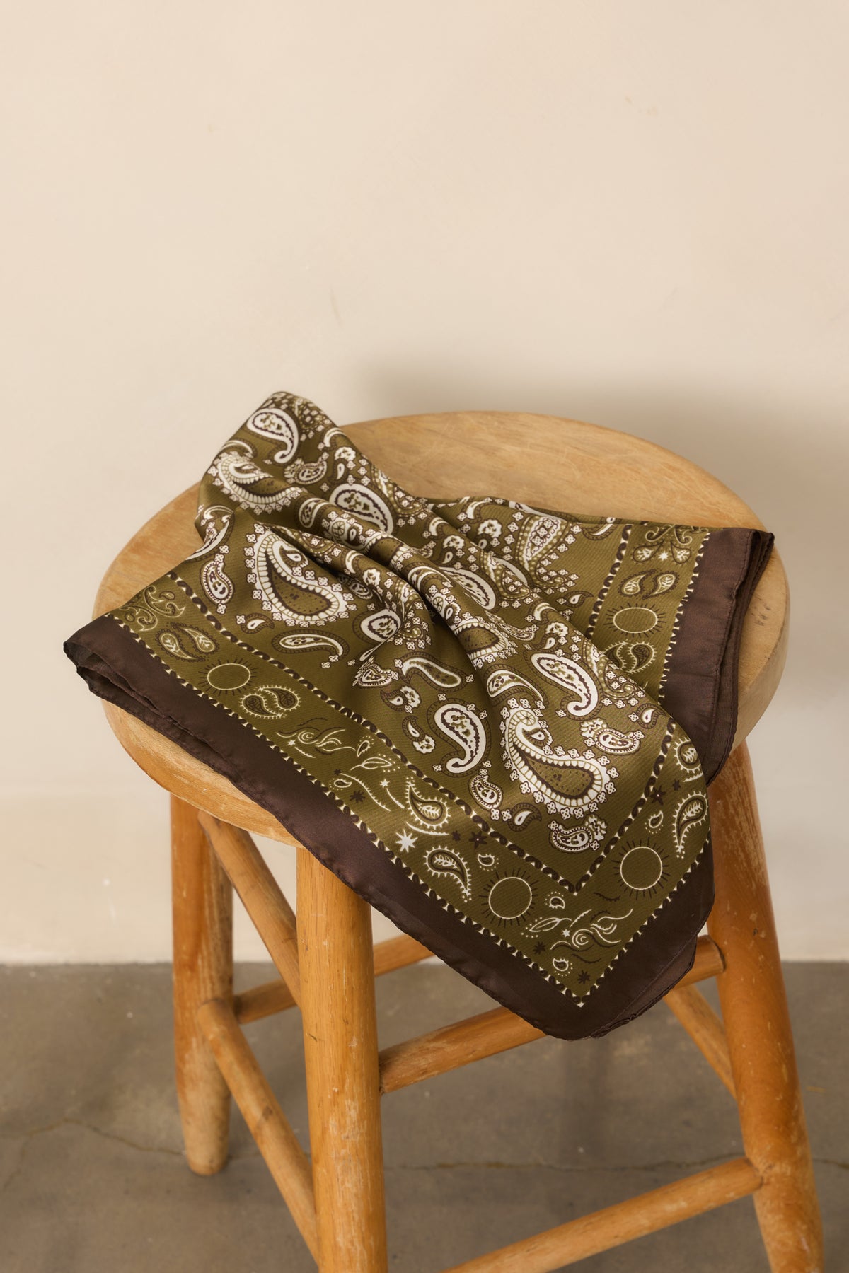 Vintage-inspired paisley scarf showcasing its satin surface, intricate pattern, and polished contrasting border.
