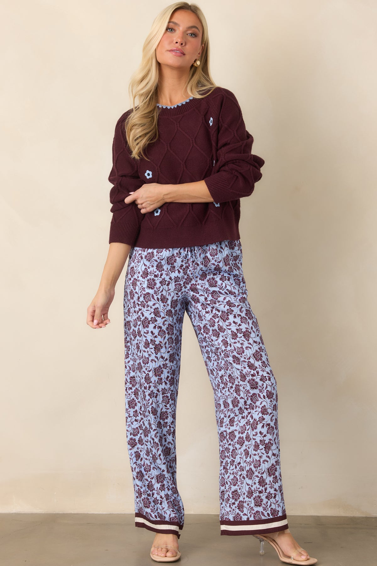 Flowing viscose-blend pants featuring a pale lilac floral print, relaxed wide legs, and striped burgundy and ivory hems.