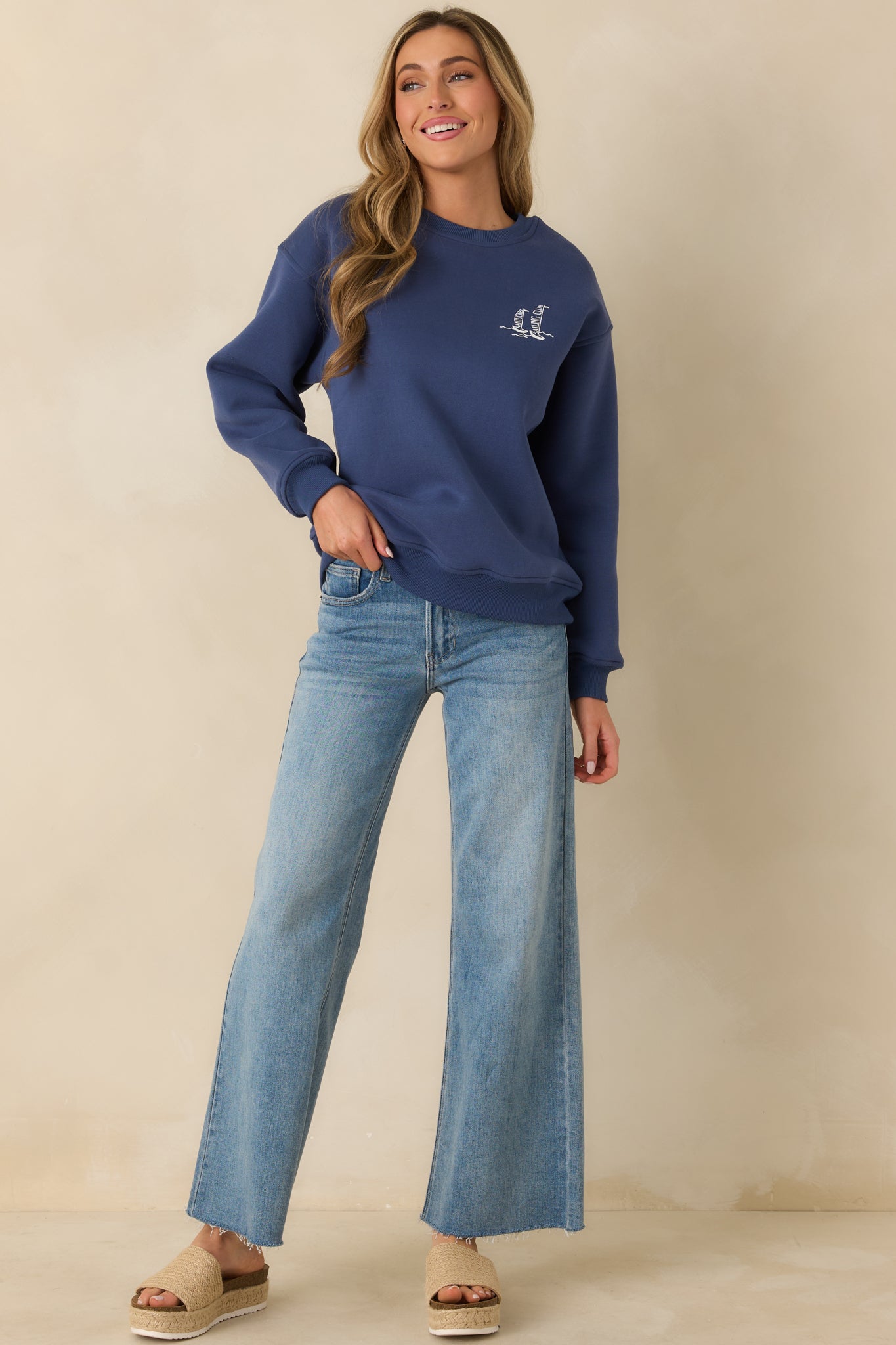 Washed navy crewneck sweatshirt with a relaxed fit, long sleeves, and a small sailboat graphic on the chest.