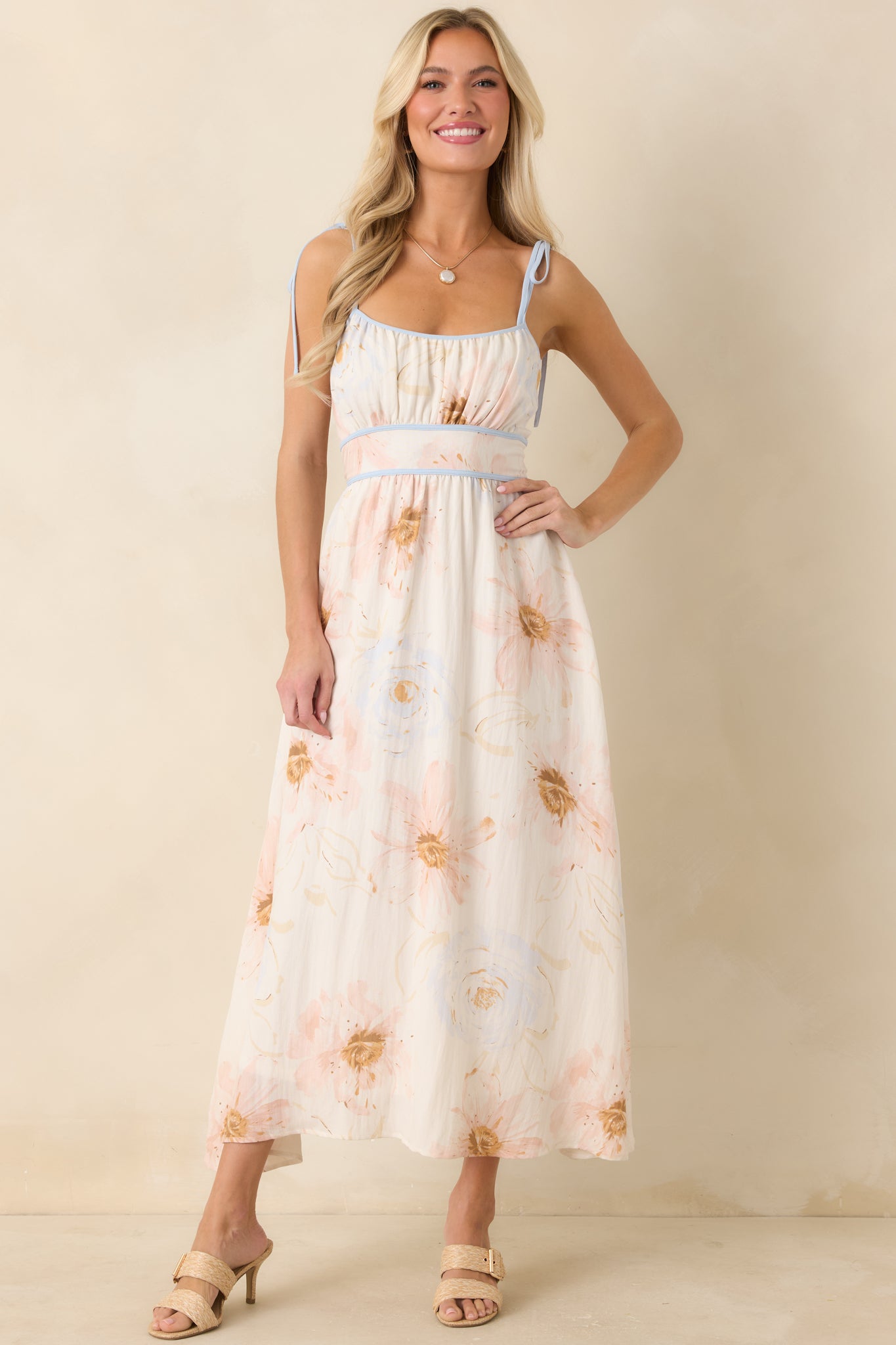 Watercolor floral midi dress with warm blush accents, muted blue details, and a relaxed skirt.
