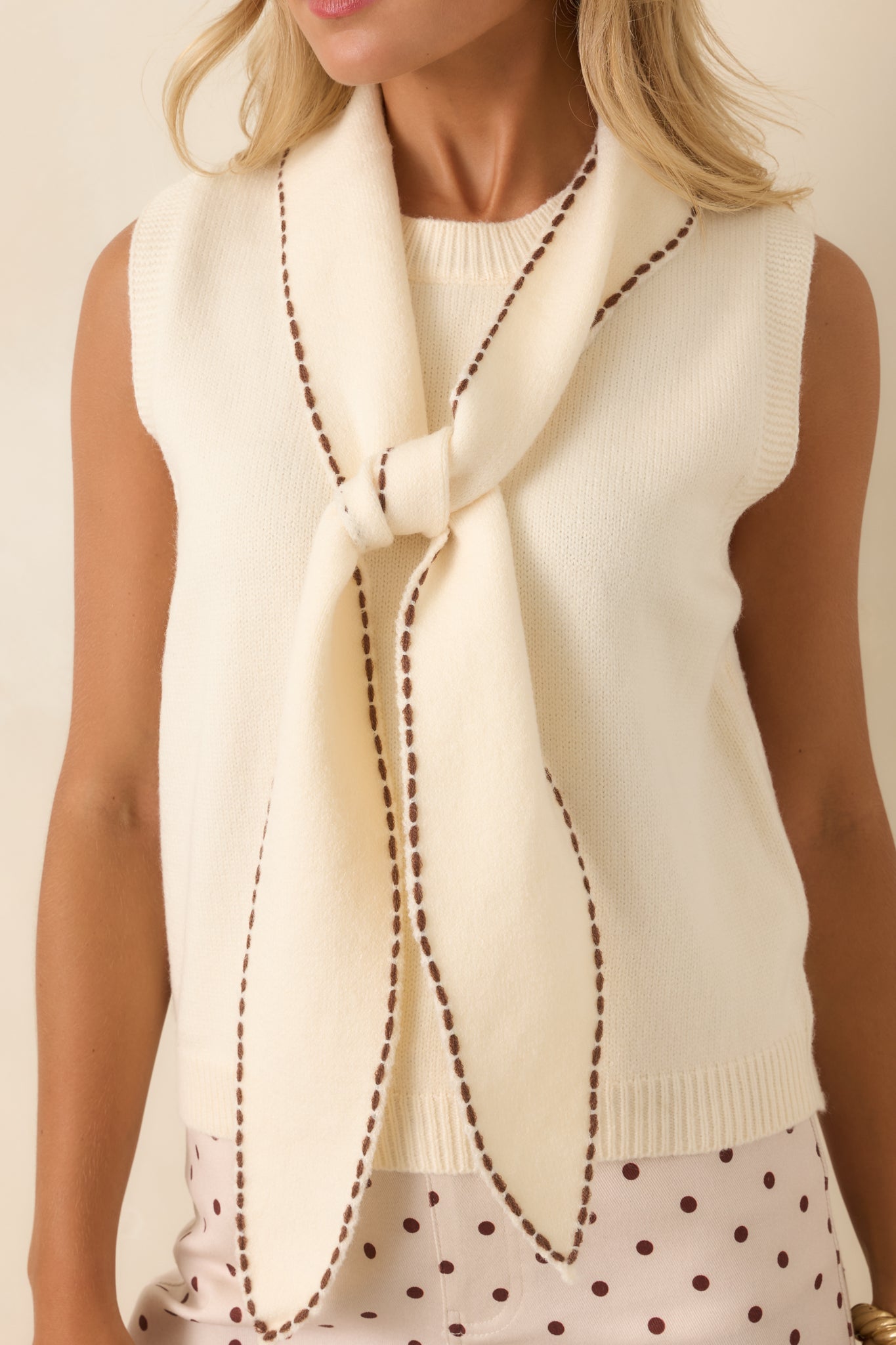 Detailed view of the scarf collar, brown whipstitch trim, ribbed neckline, and knit texture.