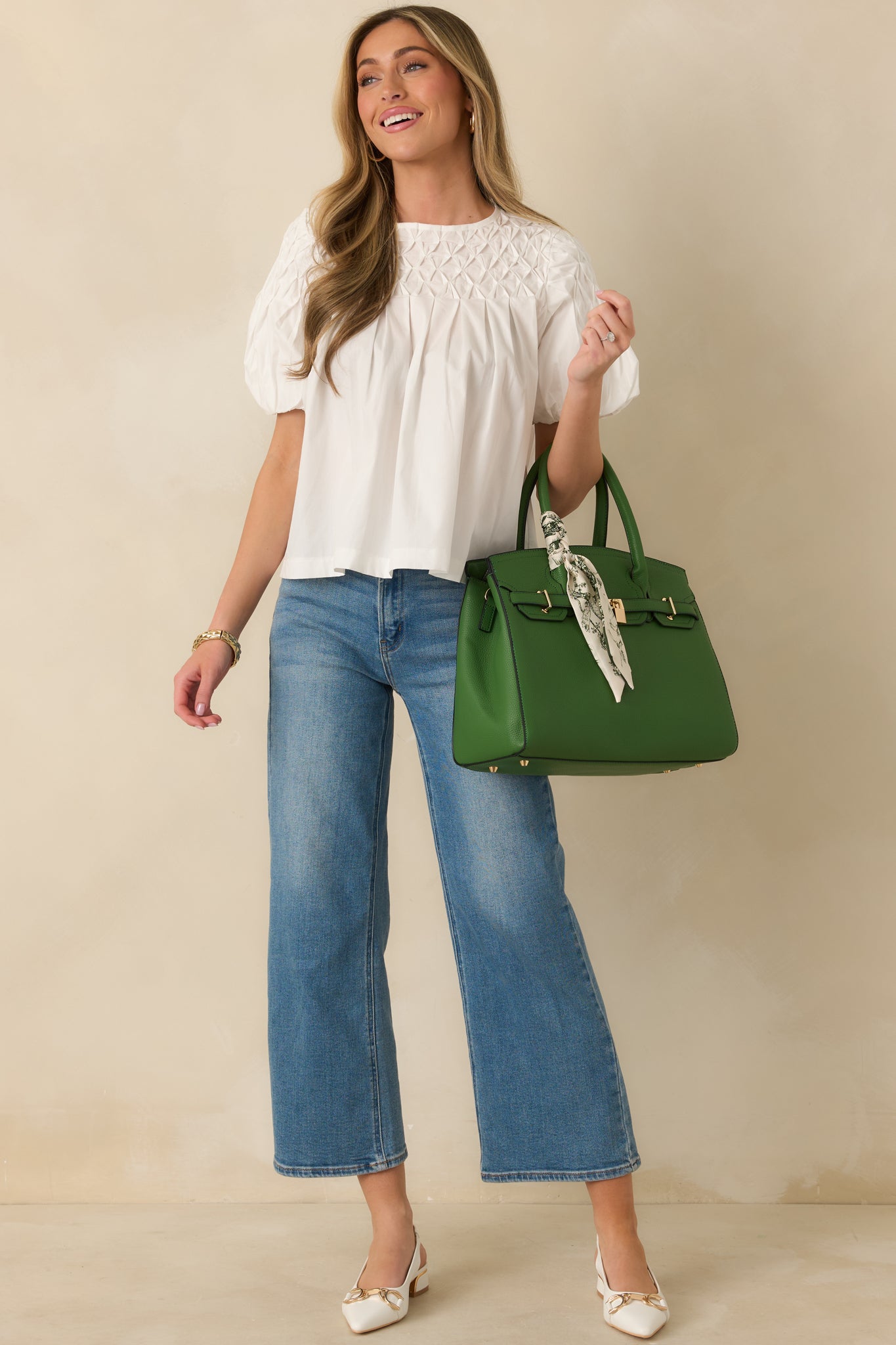 Front view of a white blouse featuring a smocked lattice yoke, soft puff sleeves, and a relaxed silhouette.