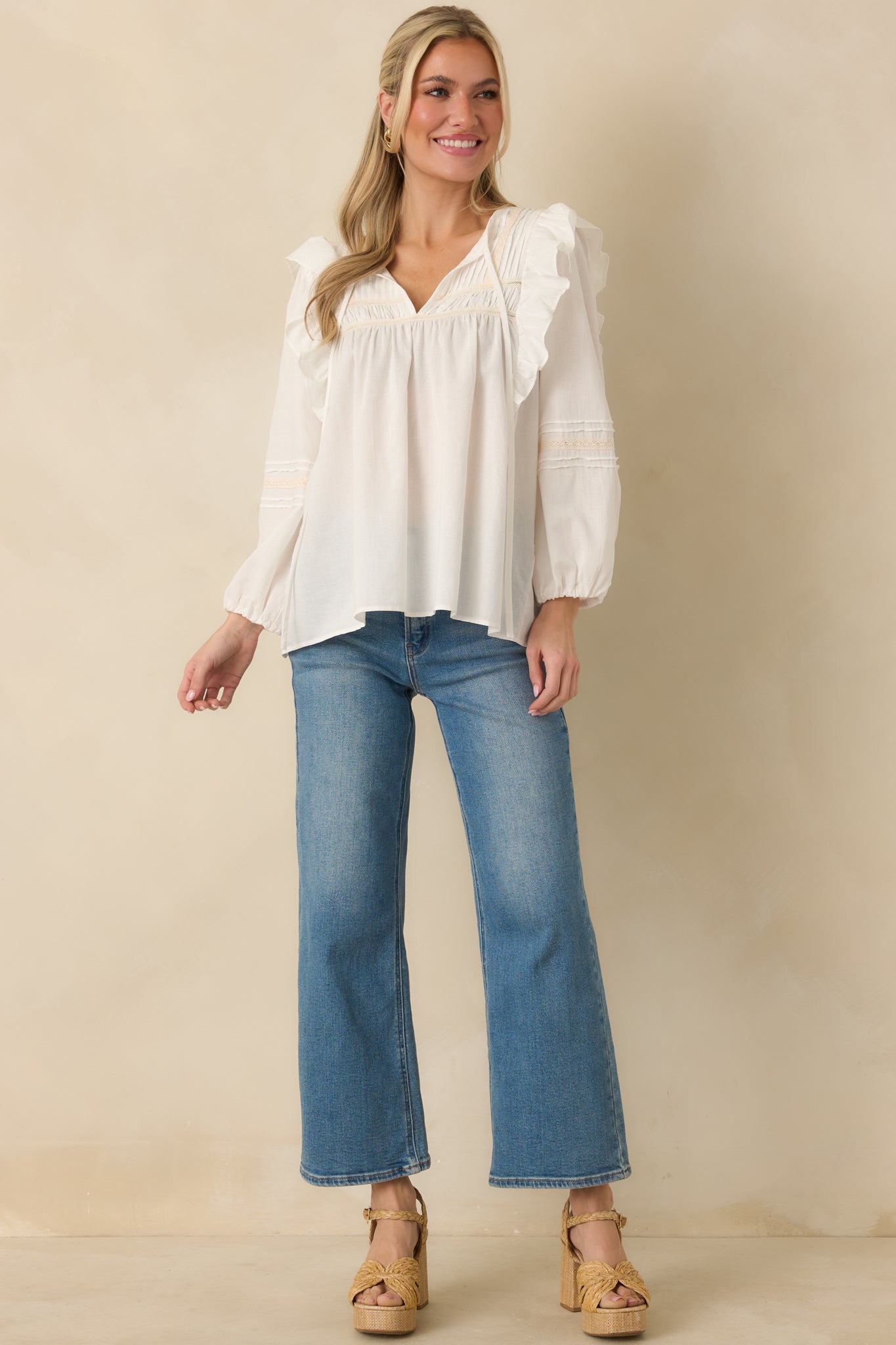 White blouse with sheer long sleeves, elastic cuffs, and textured lace trim along the neckline.