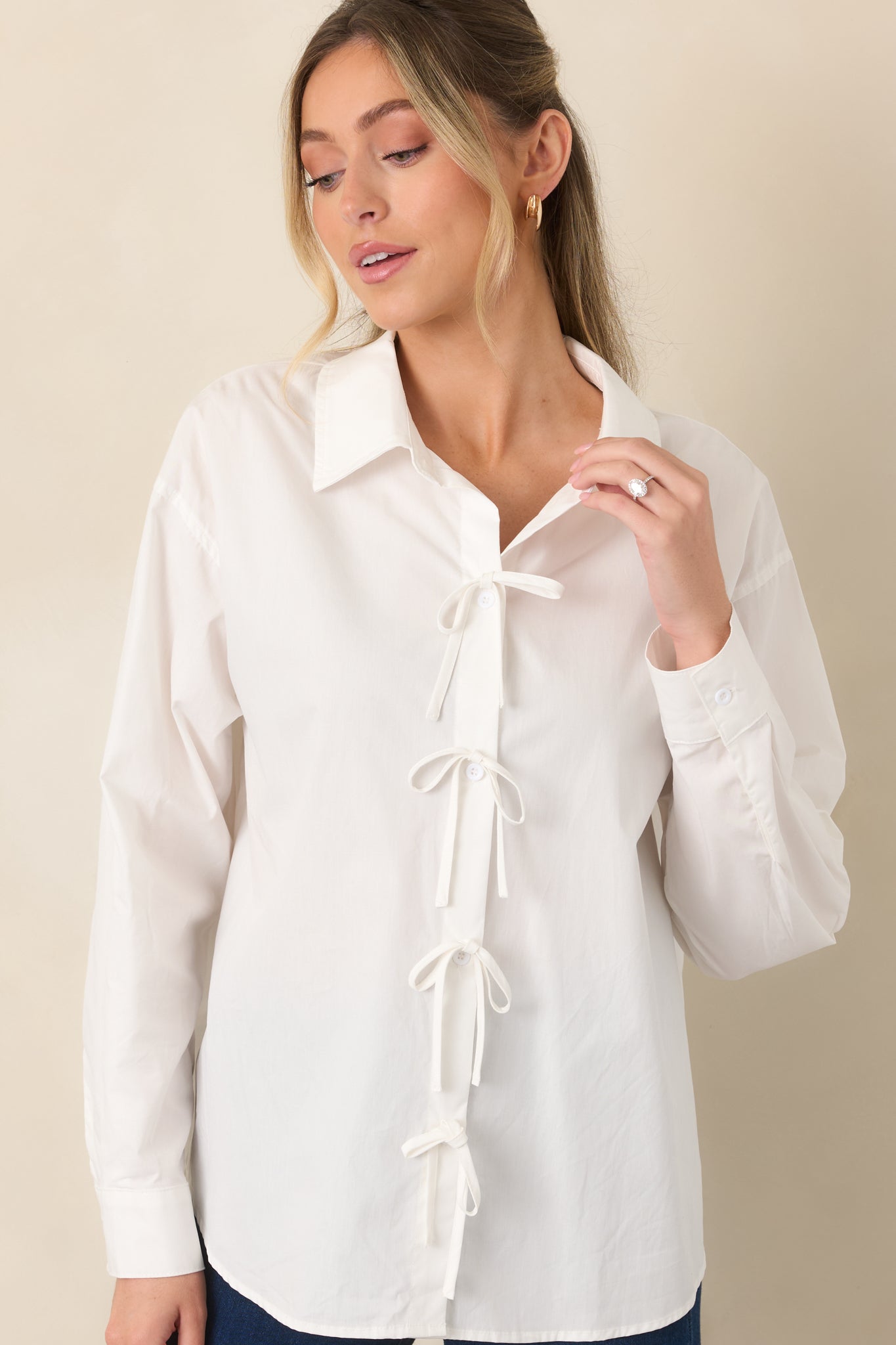 Front detail of the white button-front top emphasizing the neat collar, evenly spaced buttons, and decorative bow details.