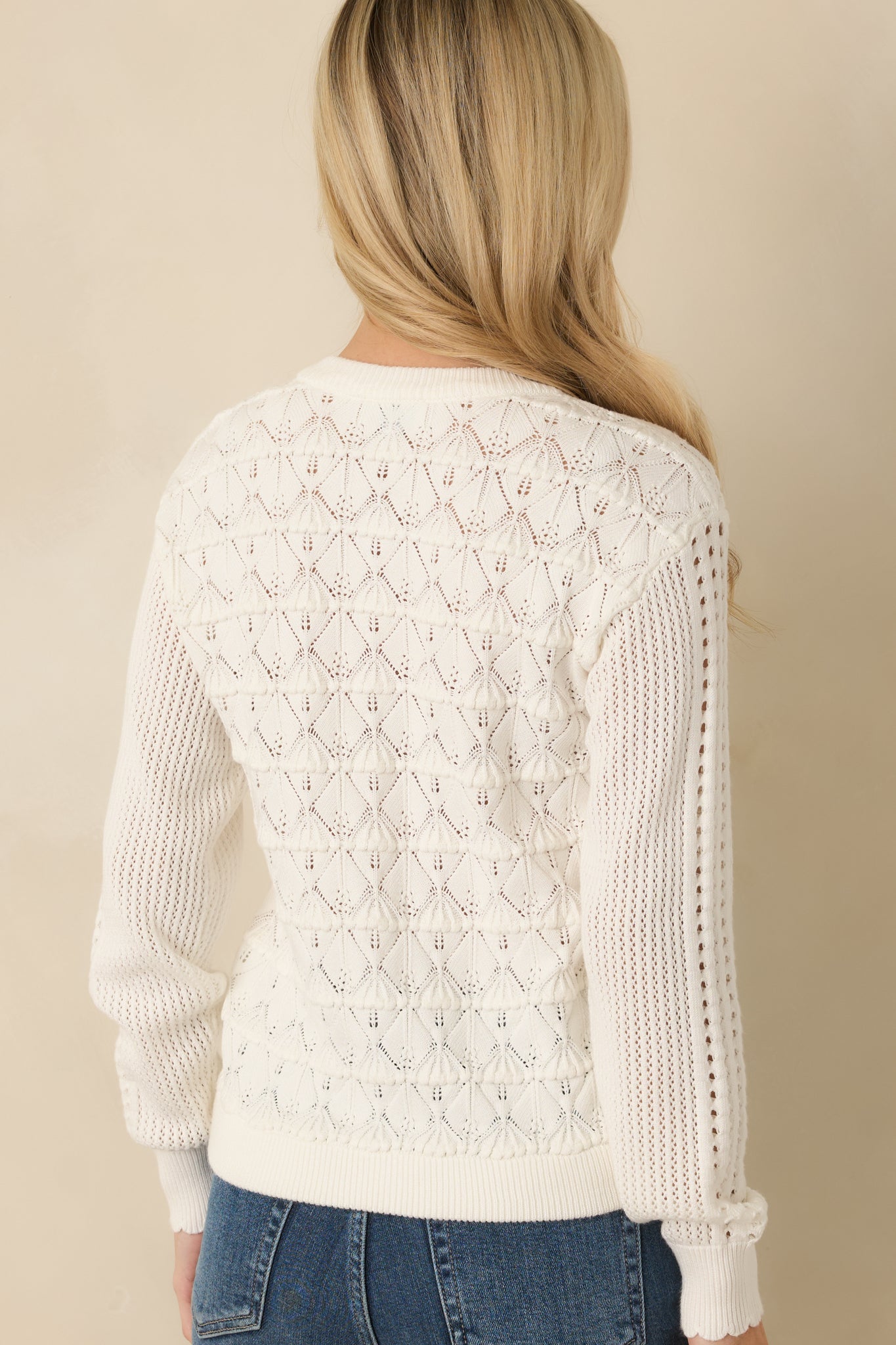 Back view of the white cardigan featuring a softly tailored silhouette and lightweight pointelle knit finish.