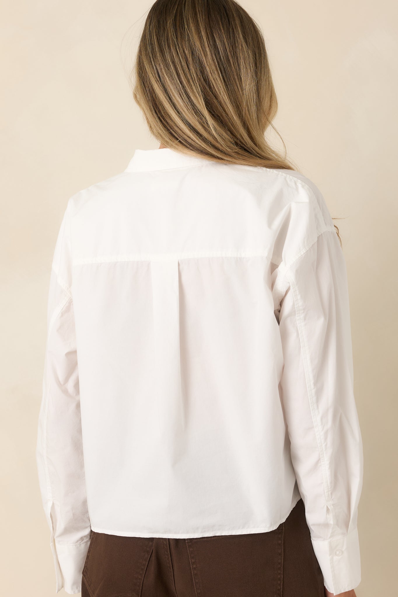 Back view of the crisp white cotton shirt featuring a relaxed fit, cropped hem, and clean classic silhouette.