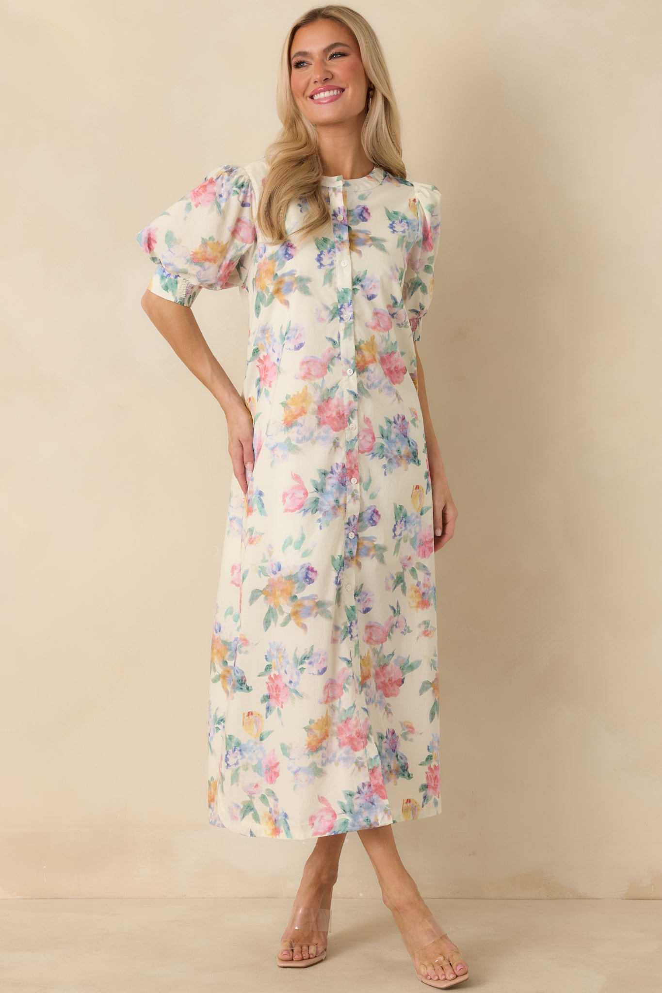 White cotton maxi dress with soft floral print, round neckline, short puff sleeves, and airy flowing skirt.