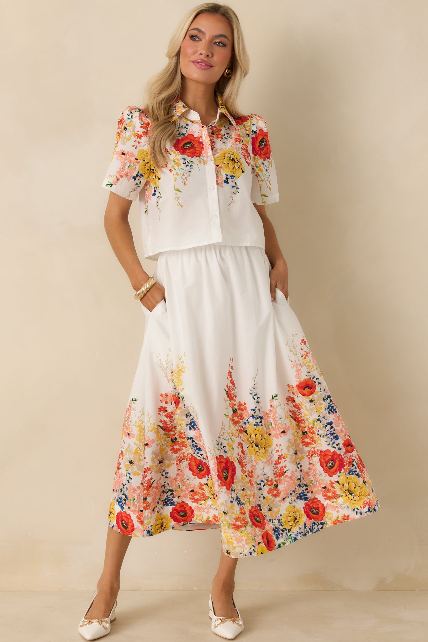 White cotton maxi skirt with a flowy silhouette, high-rise elastic waistband, and multicolor floral print along the hem.